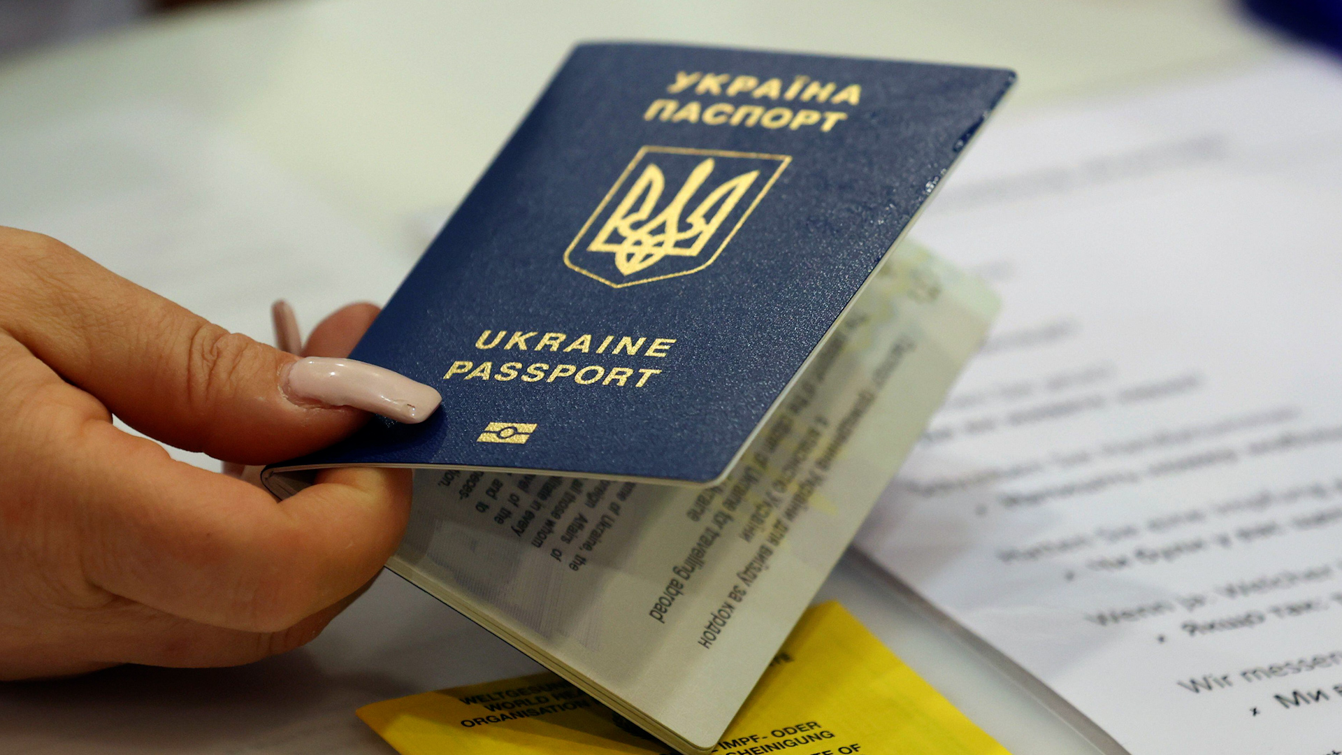 Image ID 2J262RY Employee holds Ukraine passport in registration area for vaccination campaign for Ukrainian refugees at a centre in Germany 300322 CREDIT BODO SCHACKOW, DPA-ZENTRALBILD, DPA, ALAMY