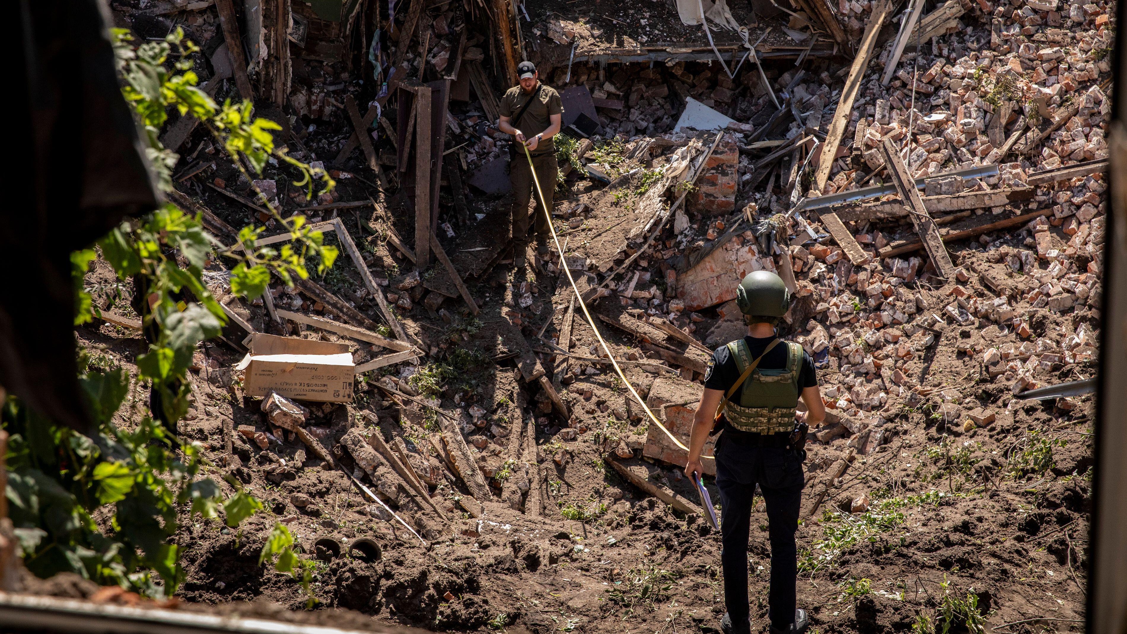Image ID 2JGDHMC Ukrainian soldiers measure a crater in Kharkiv after Russian cruise missile hit the city 09072022 CREDIT Alex Chan Tsz Yuk,ZUMA Press Wire, Alamy Stock Photo.jpg