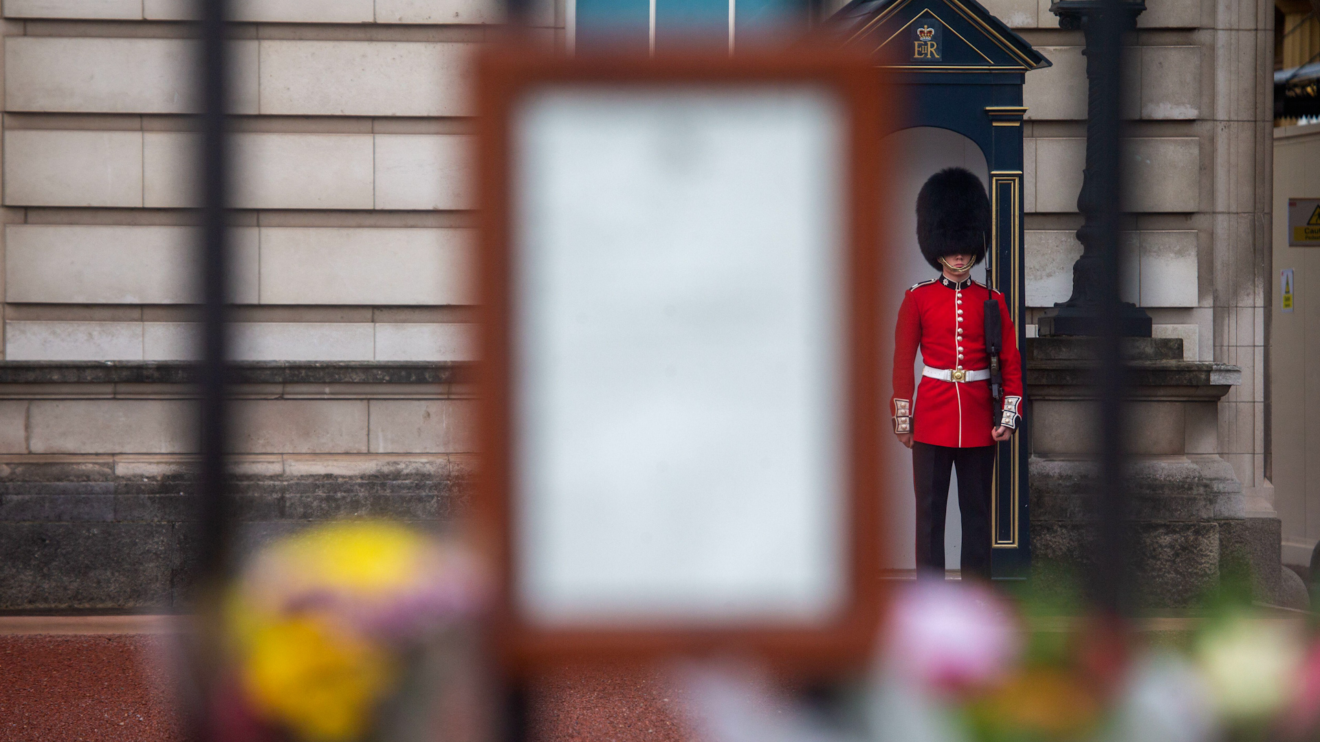 Notice of the Queen's death on the gates of Buckingham Palace, with a guard in the background