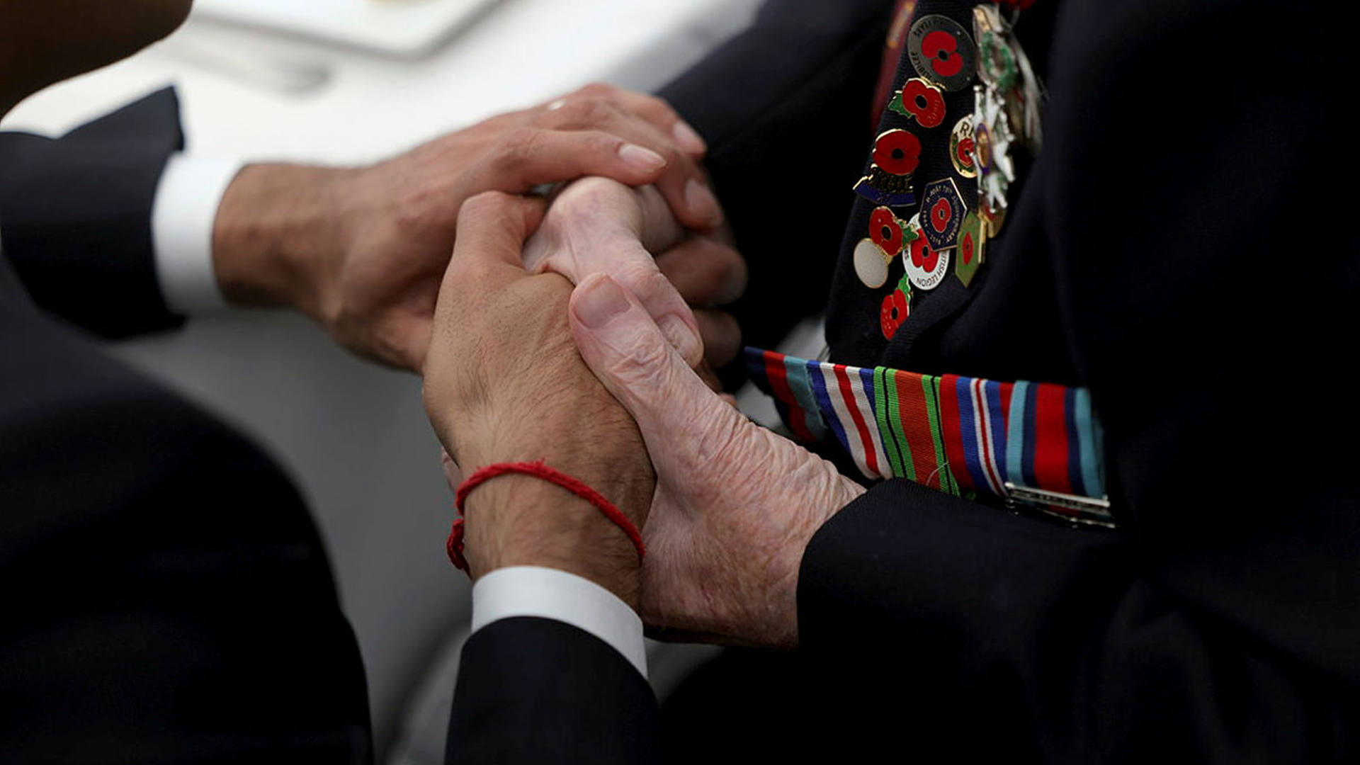 Image of the Prime Minister Rishi Sunak (left), seen here holding the hands of a veteran at the British Normandy Memorial in Ver-sur-Mer France 060624 CREDIT MOD.png