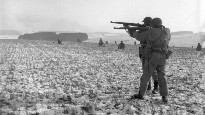 Infantrymen from the 28th Infantry Division with their rifles raised in a farm field near Clervaux, Luxembourg, during the Battle of the Bulge. CREDIT US Army
