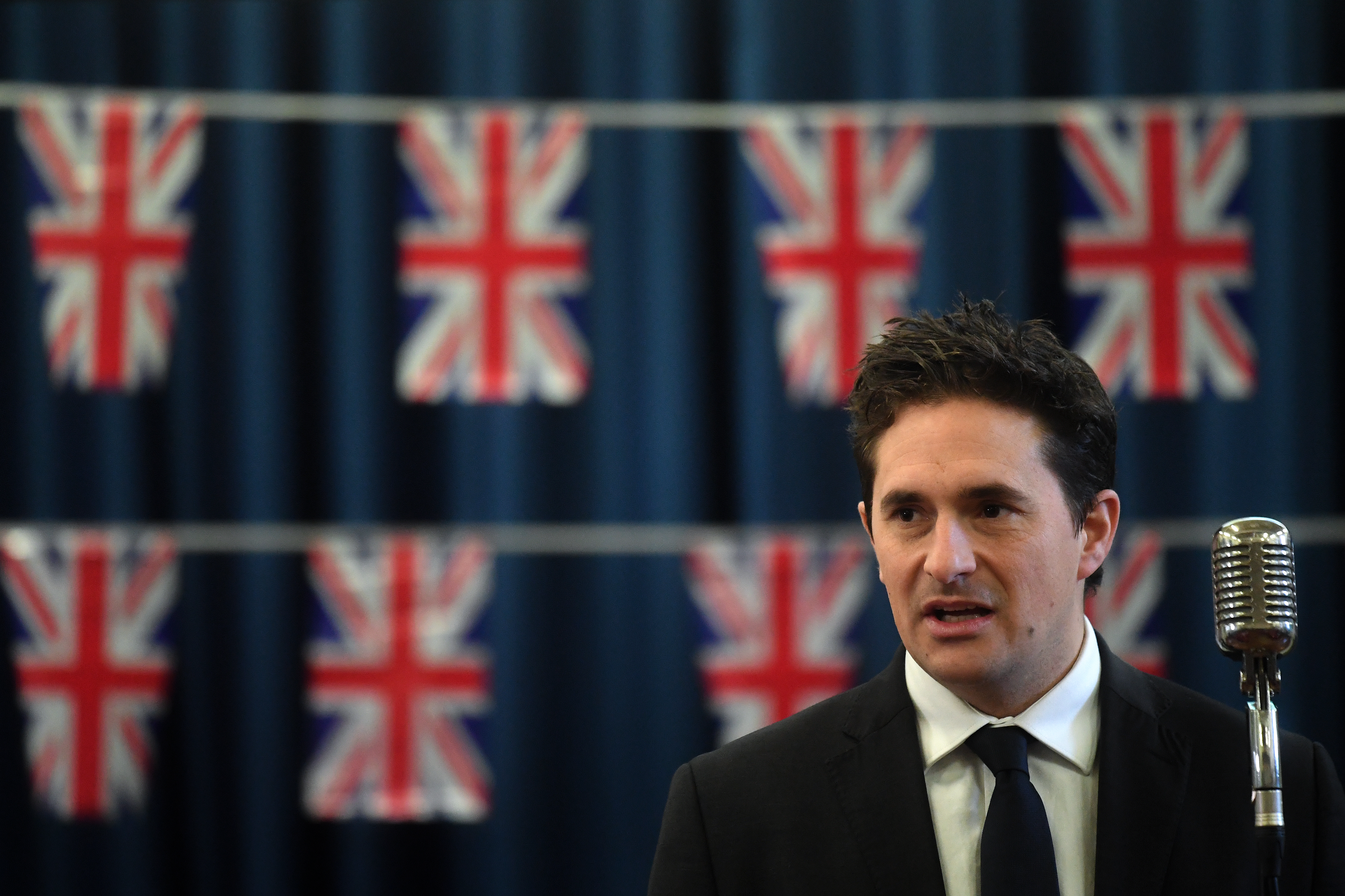 Johnny Mercer speaking with Union Flags behind him