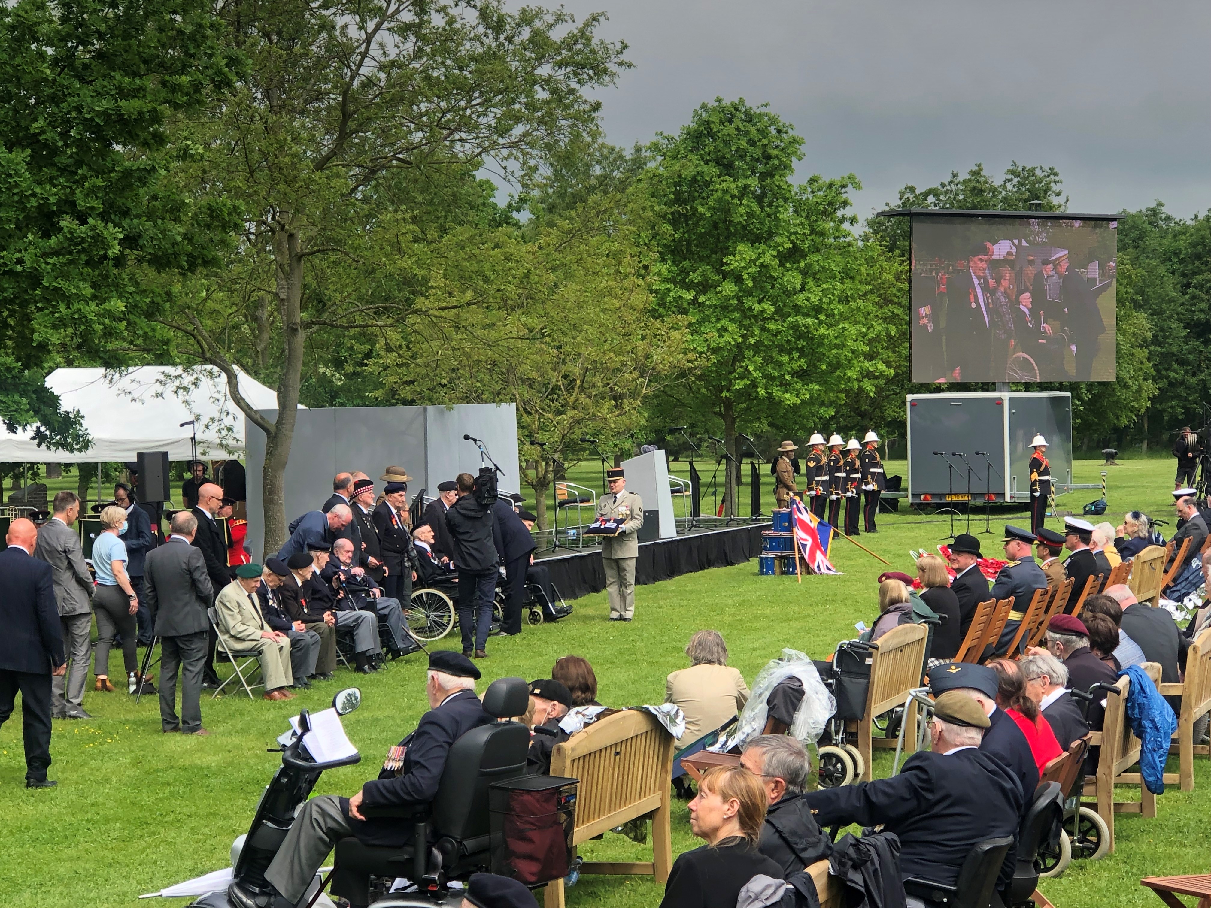 Legion d’honeur presented in the far distance as the British Normandy Memorial ceremony livestreamed at National Memorial Arboretum.
