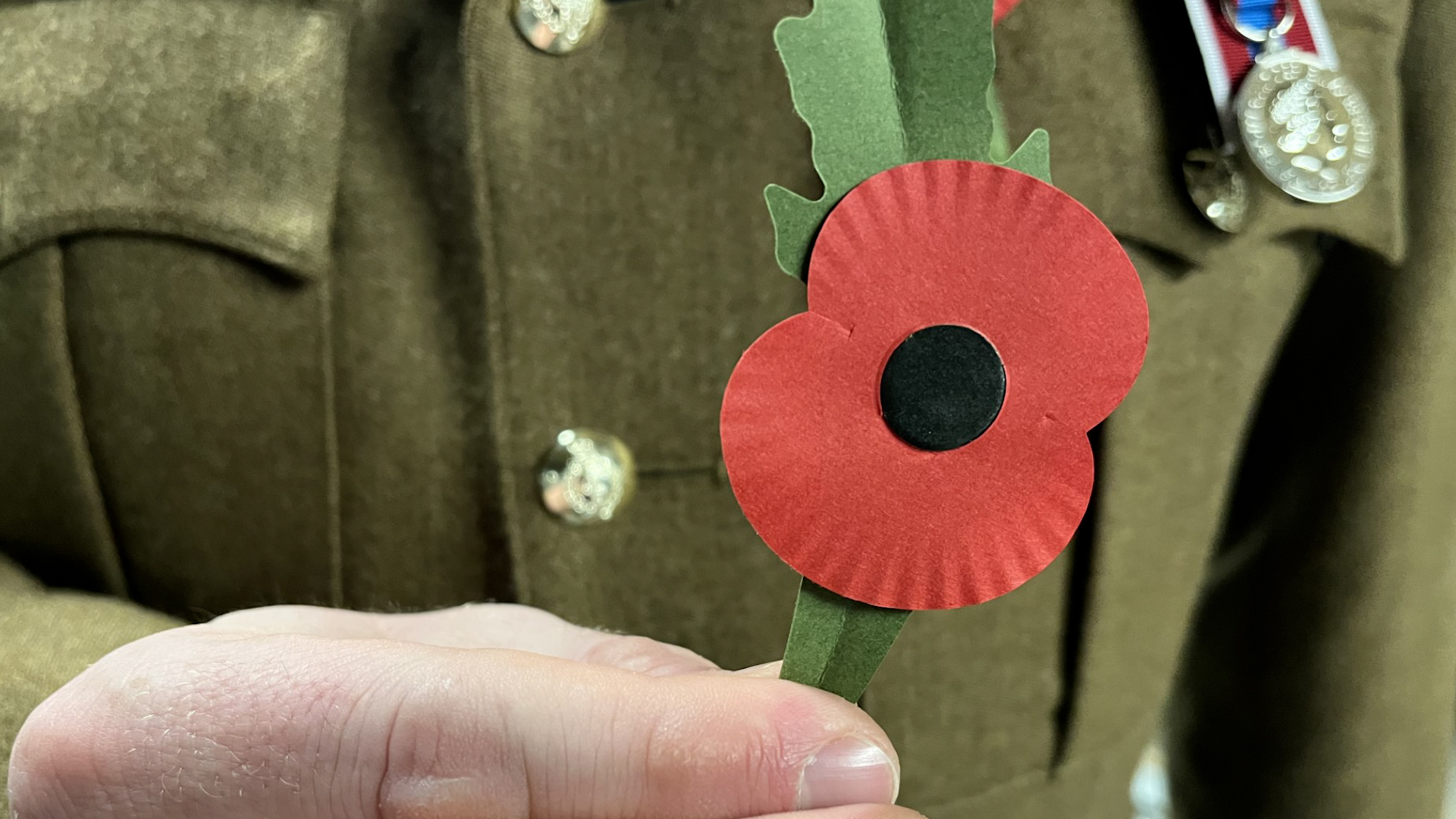 	Member of the British Armed Forces holding up the RBL's new plastic poppy 