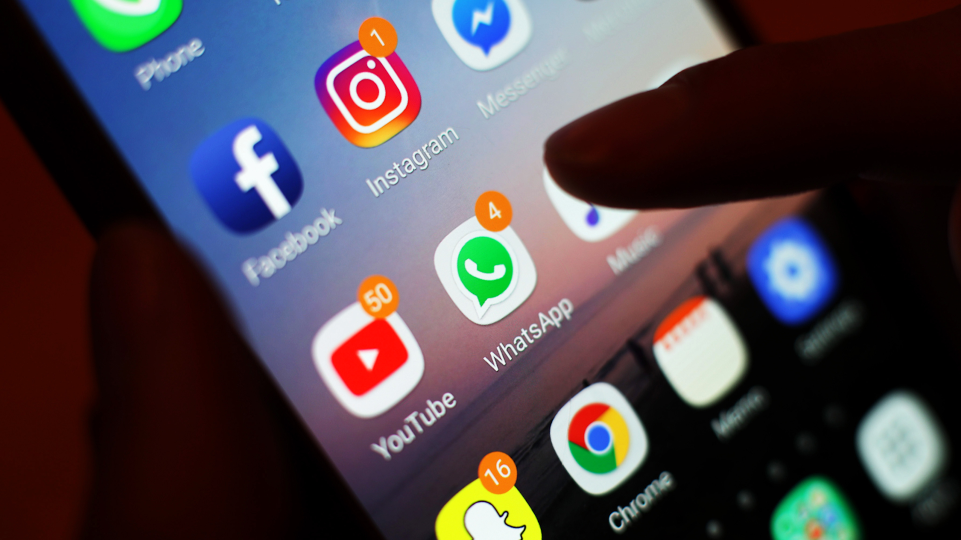 Someone holding a mobile phone with apps on screen