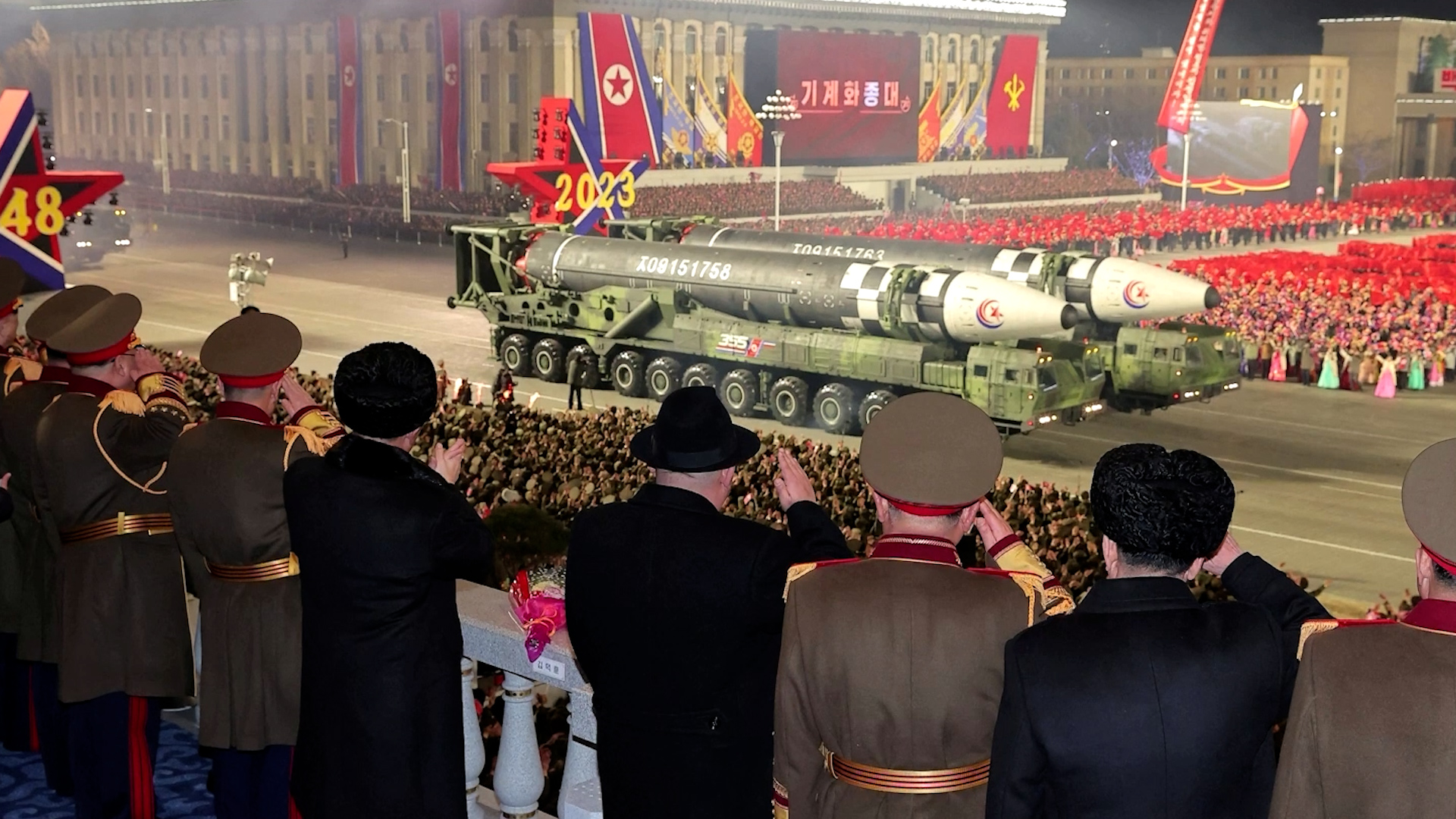 NORTH KOREAN MILITARY VEHICLES CARRYING WHAT APPEARS TO BE INTERCONTINENTAL BALLISTIC MISSILE DURING MILITARY PARADE WITH KIM JONG UN AND OFFICIALS SALUTING