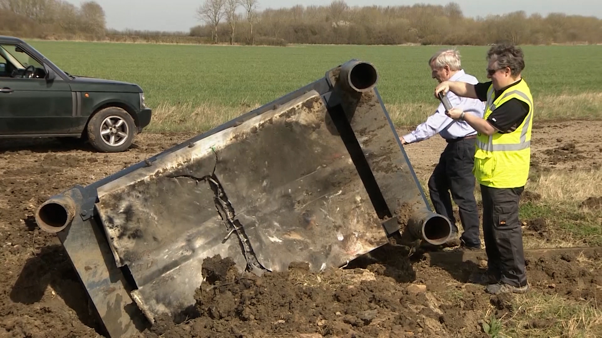 Inventor Roger Sloman (back), inspects the belly plate following a test blast.