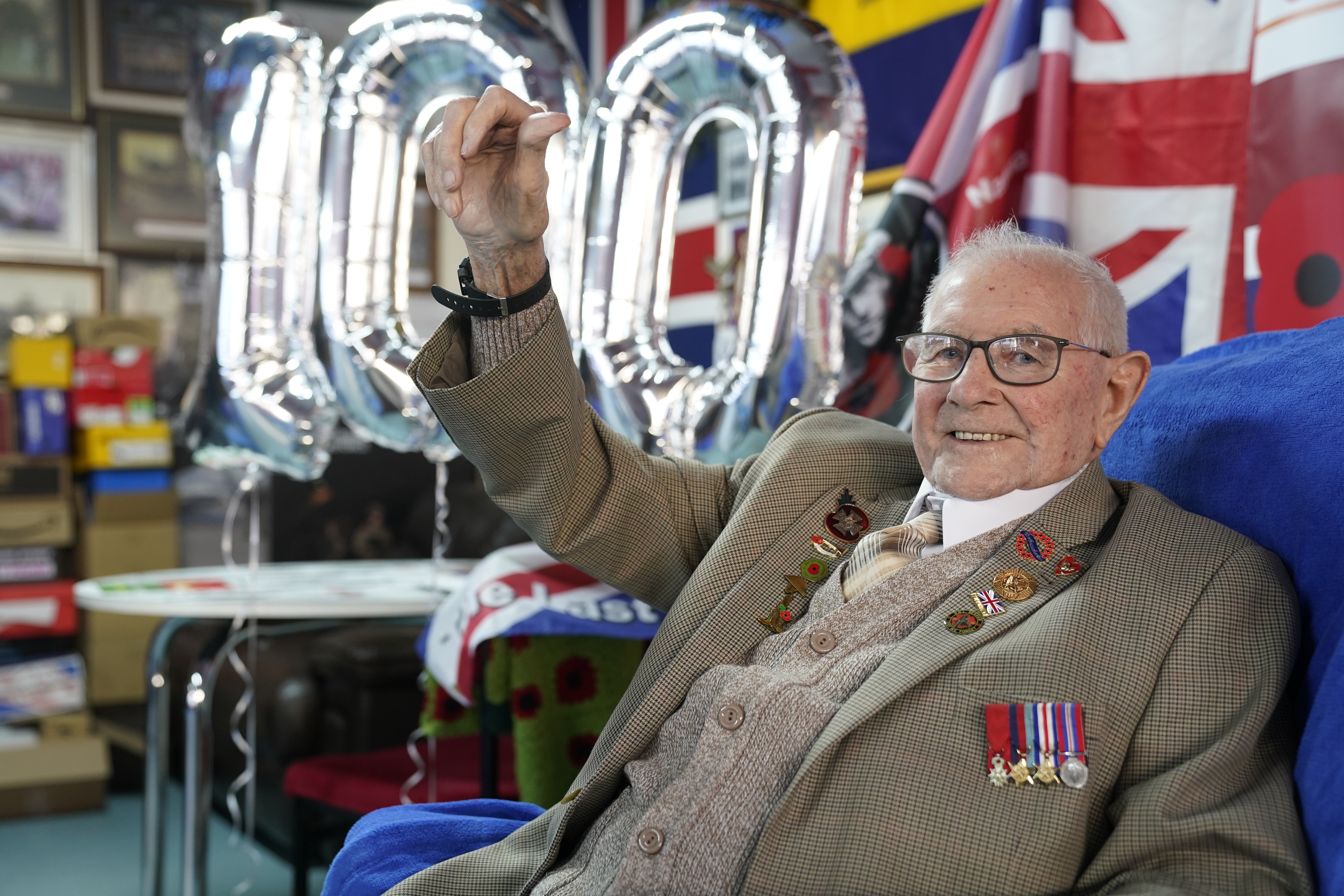 Cover image: Tommy Trotter with '100' balloons behind him (Picture: PA).