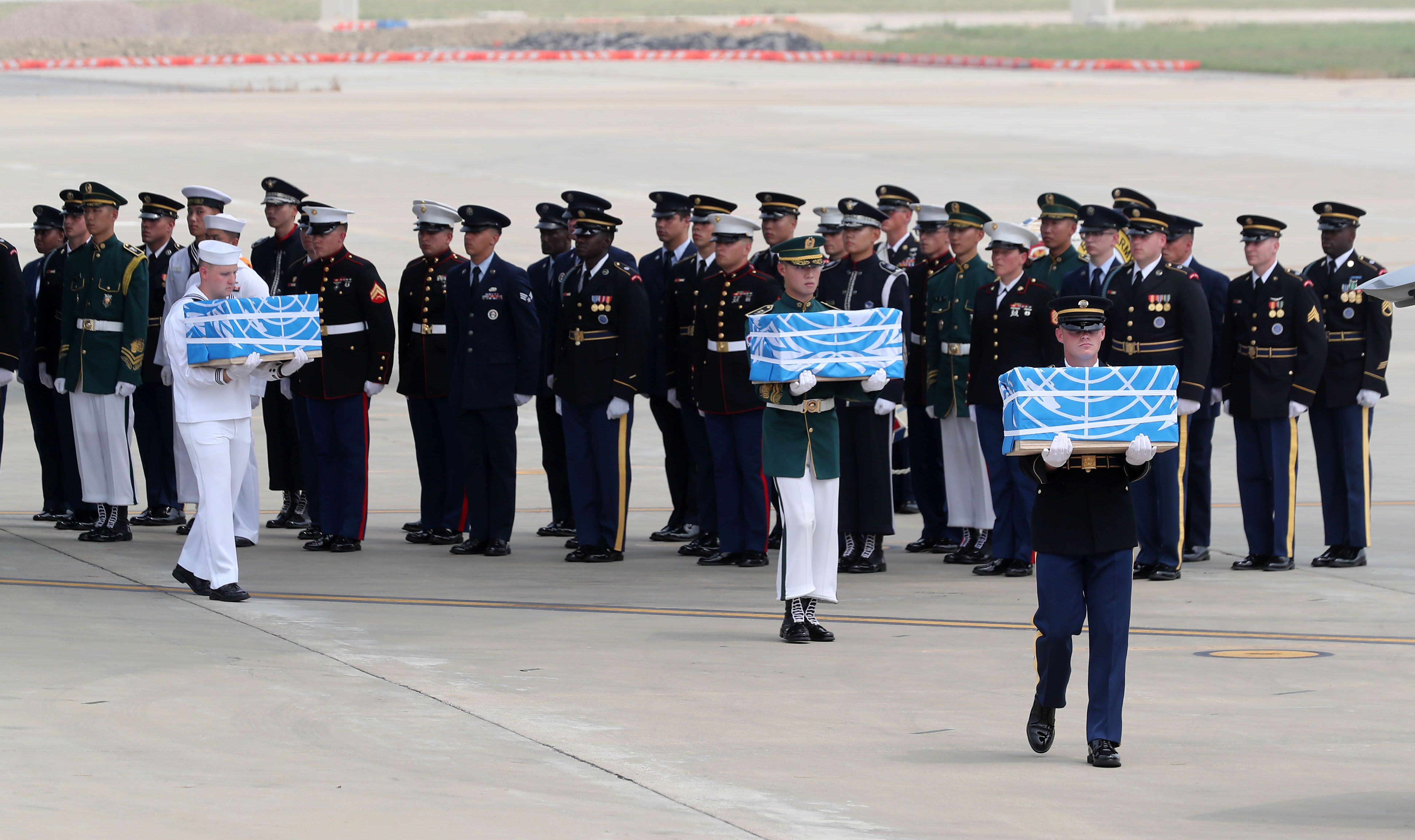 U.N. honor guards carry the boxes containing remains believed to be from American servicemen killed during the 1950-53 Korean War on the arrival from North Korea, at Osan Air Base in Pyeongtaek, South Korea, Friday, July 27, 2018.