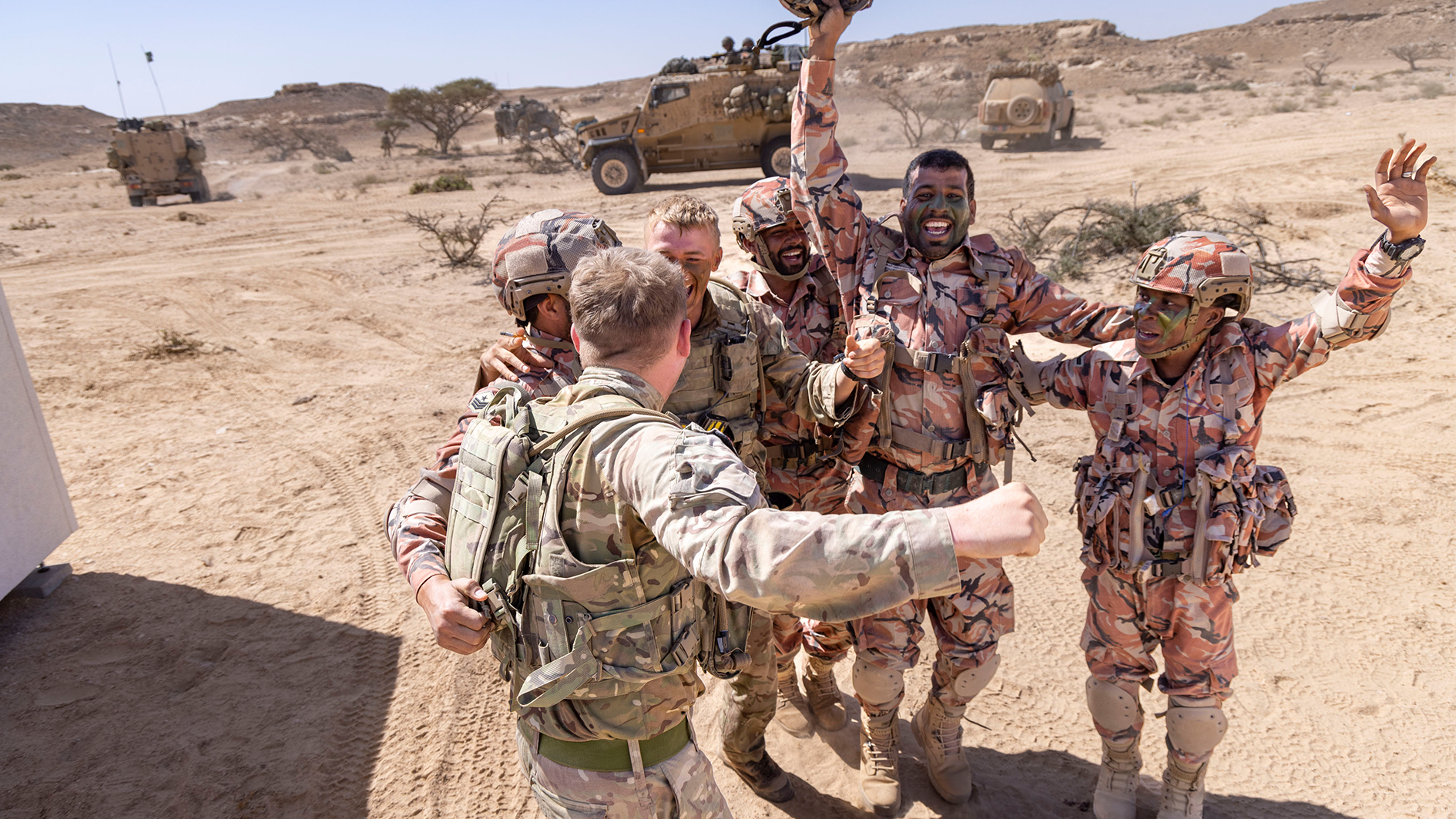 Omani and British soldiers as they complete the attack a simulated village as part of Exercise Khanjar Oman and celebrate together 180223 CREDIT MOD