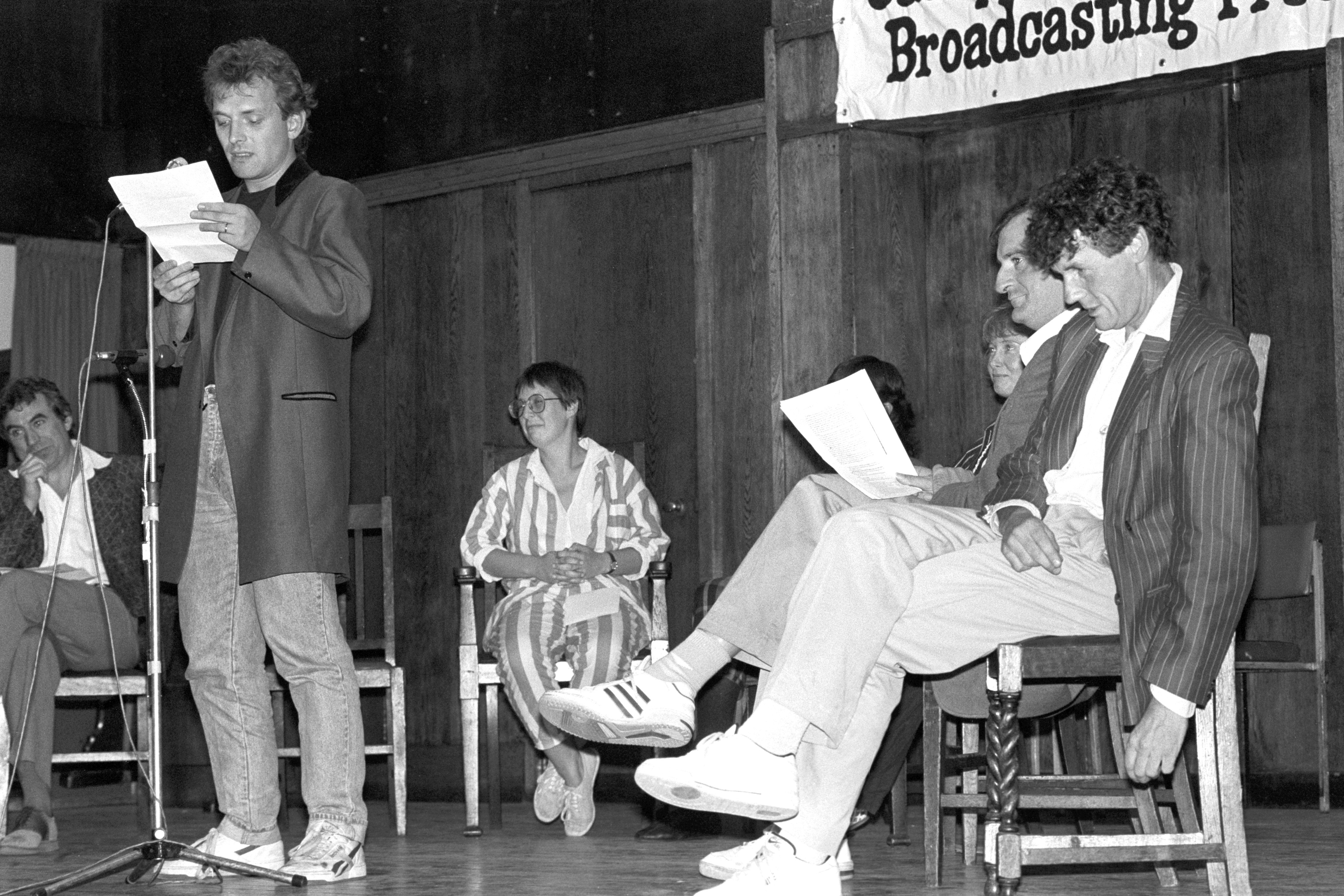 TV comedian Rik Mayall reads an extract from the banned Peter Wright book Spycatcher, at an event organised by the Campaign for Press and Broadcasting Freedom at Conway Hall in London. Former Monty Python member Michael Palin is seated on the right.