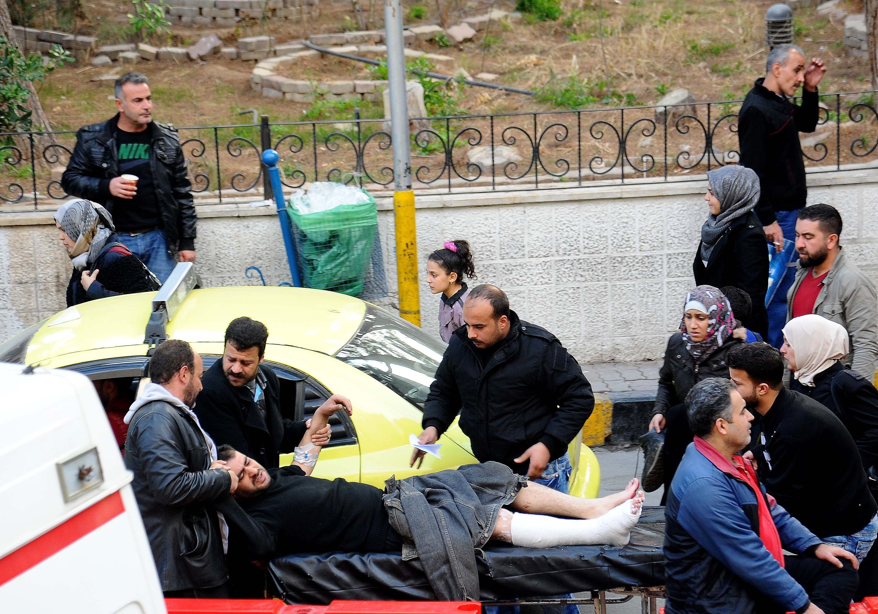 People get a wounded man into ambulance in Damascus, capital of Syria. CREDIT PA