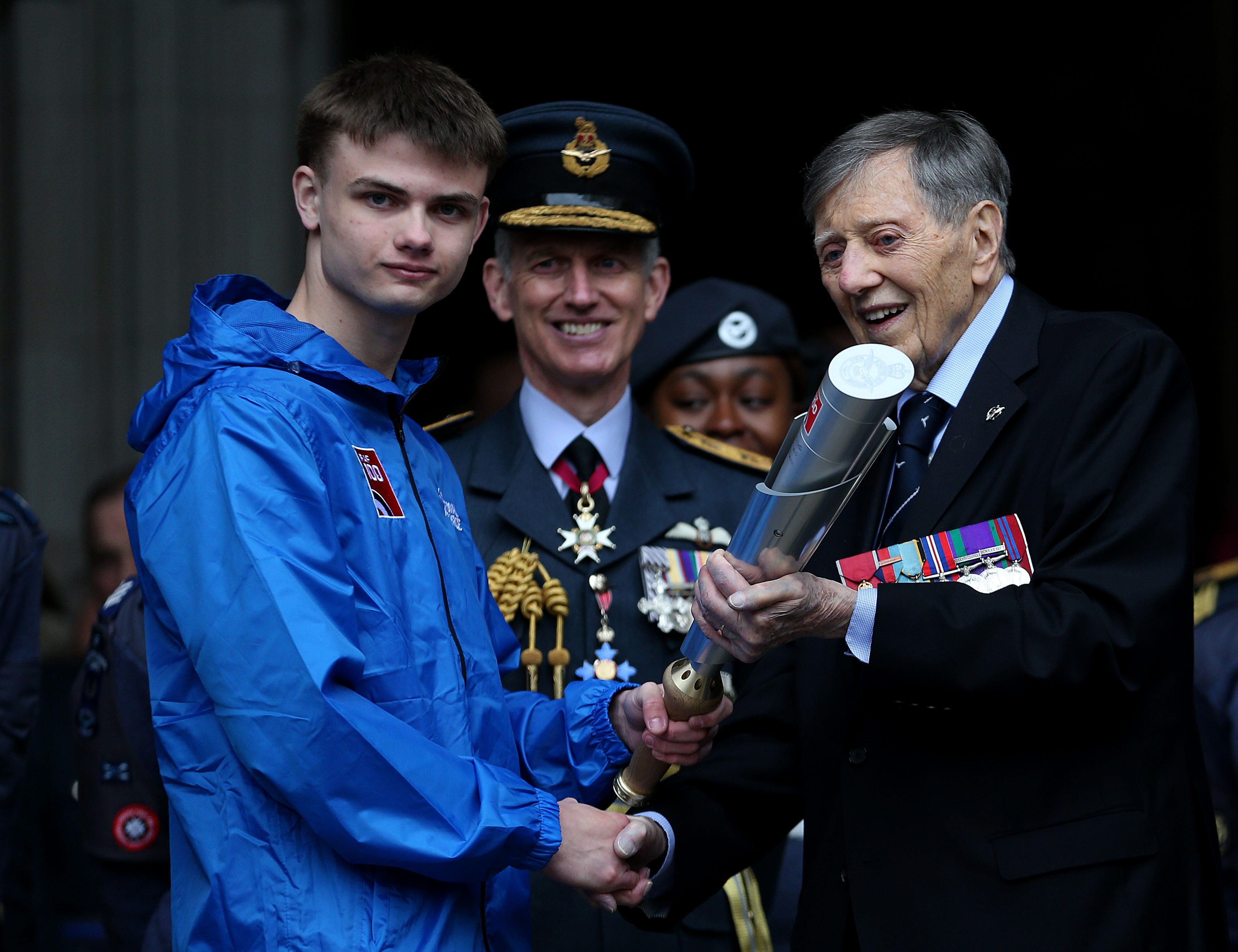 One of the youngest serving members of the RAF, Aircraftsman Adam Wood, 16, is handed the baton by Royal Air Force veteran, Air Commodore Charles Clarke (right) outside the Royal Courts of Justice in London Credit: PA Images
