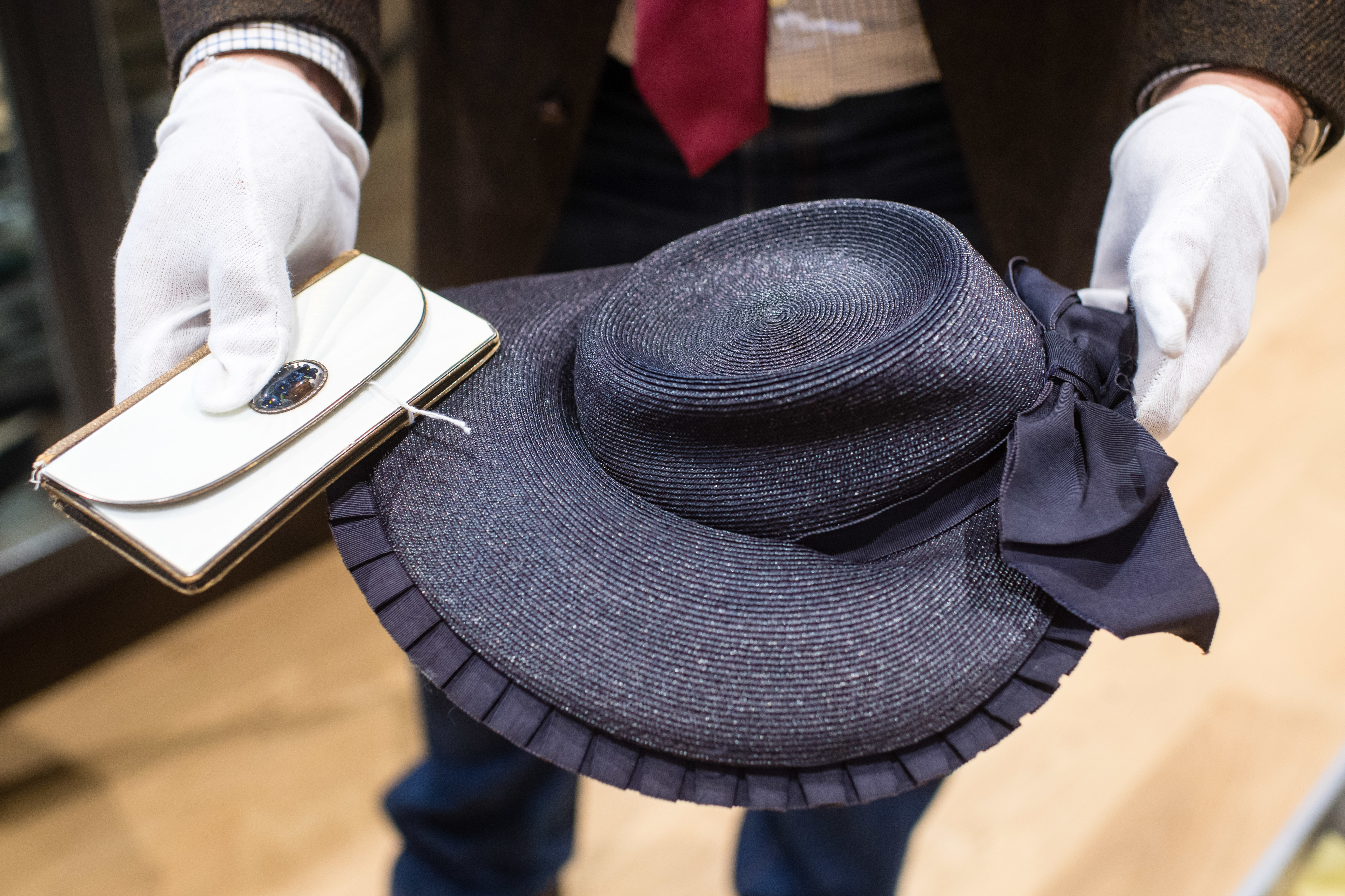 Partially painted leather wallet (l) and a black and blue straw hat by Eva Braun in his hands at the auction house Hermann Historica 201119 CREDIT Matthias Balk DPA PA Images.jpg