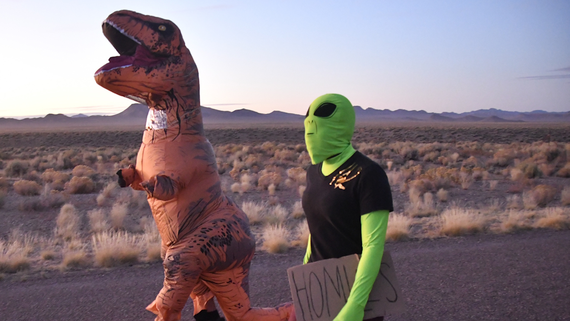 People dressed a a t-rex and alien at Area 51 Alienstock event