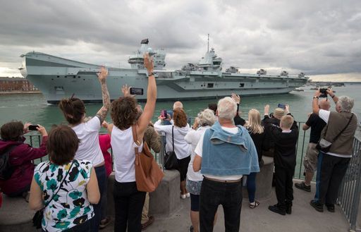 People wave from the Round Tower as the Royal Navy aircraft carrier HMS Queen Elizabeth leaves Portsmouth Naval Base as it sets sail for flight trials 