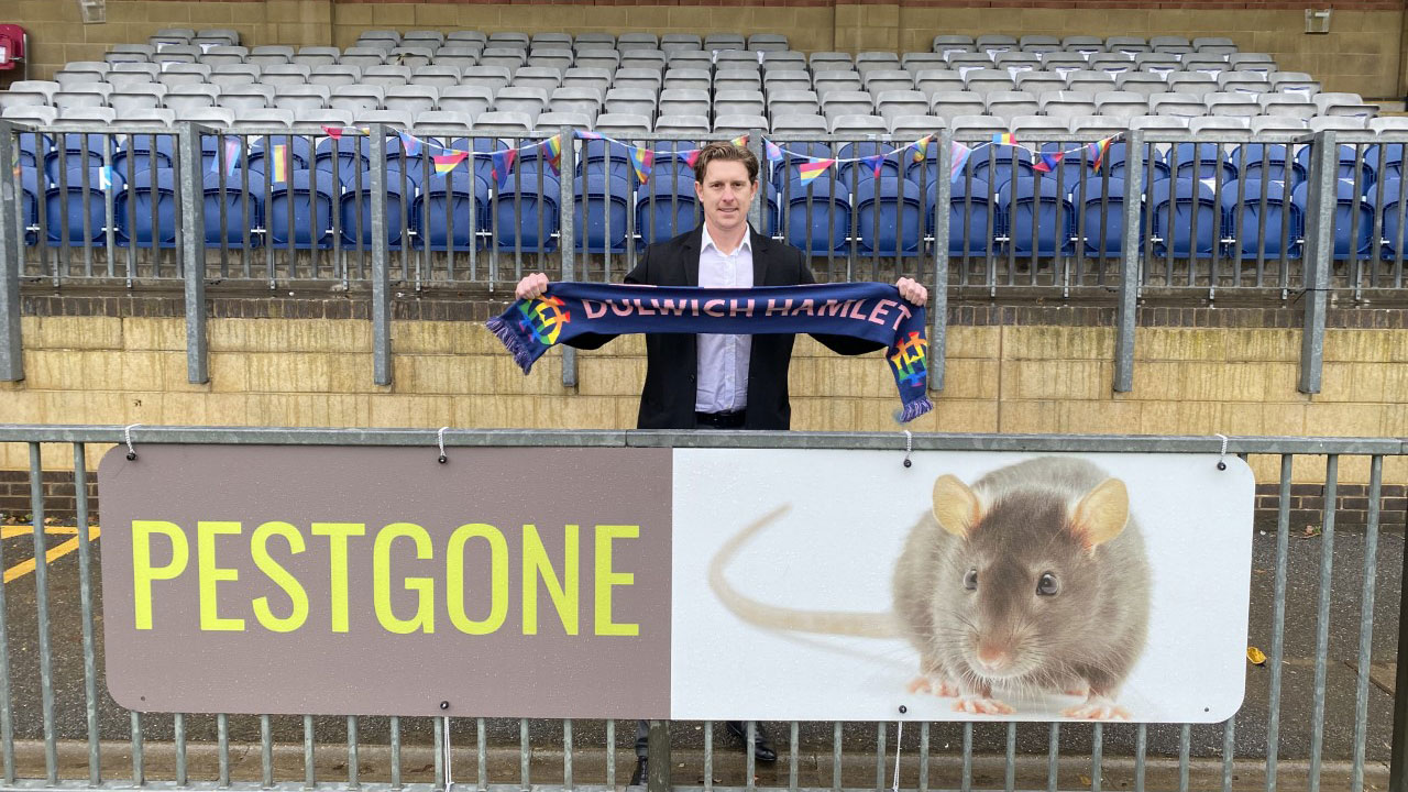 Pest Gone banner featuring a rat with Mark Moseley at Dulwich Hamlet FC's ground CREDIT Mark Moseley
