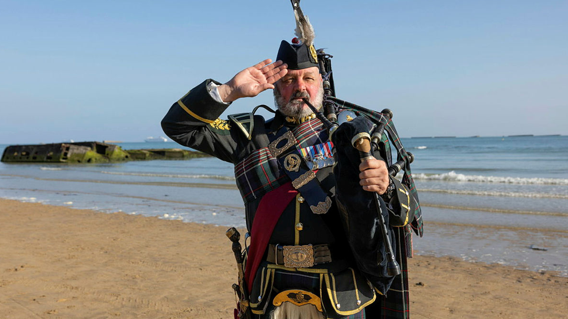 Pipe Major Trevor Macey-Lillie salutes after his landing at Gold Beach (Picture: MOD)