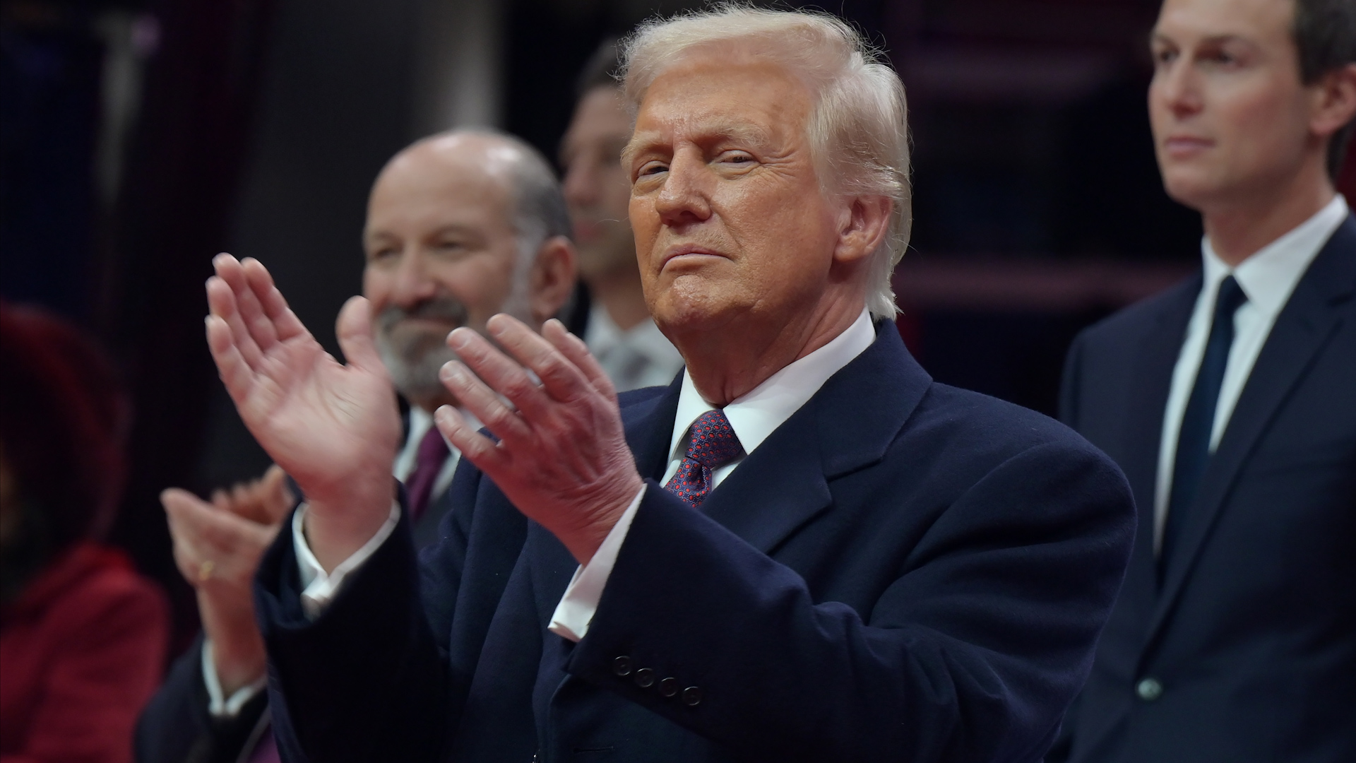 President Donald Trump applauds following a student band’s performance during the inaugural parade