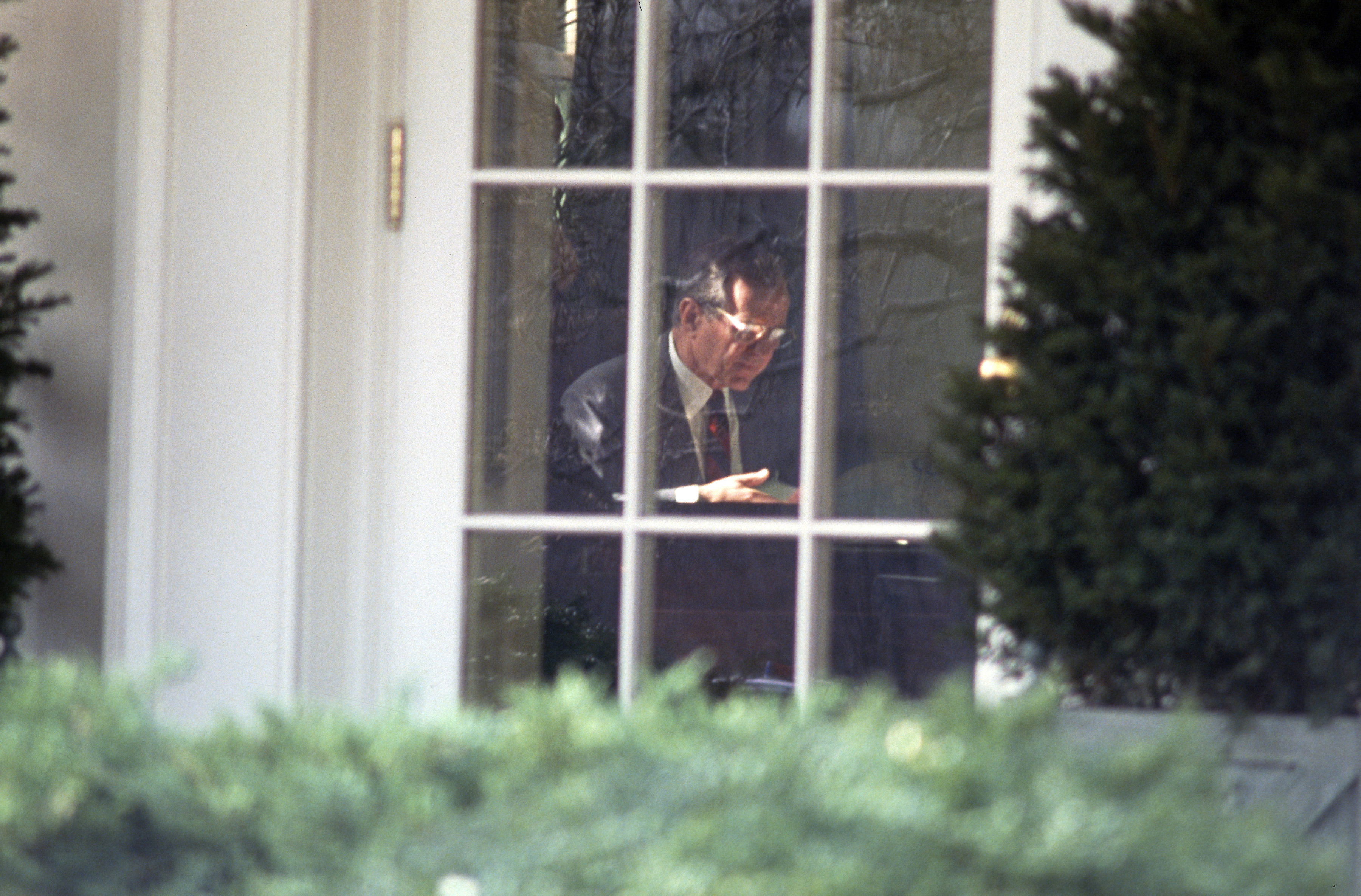 President George H.W. Bush in the White House Oval Office writing on a statement rejecting the proposed Soviet peace agreement to end the Gulf War with Iraq