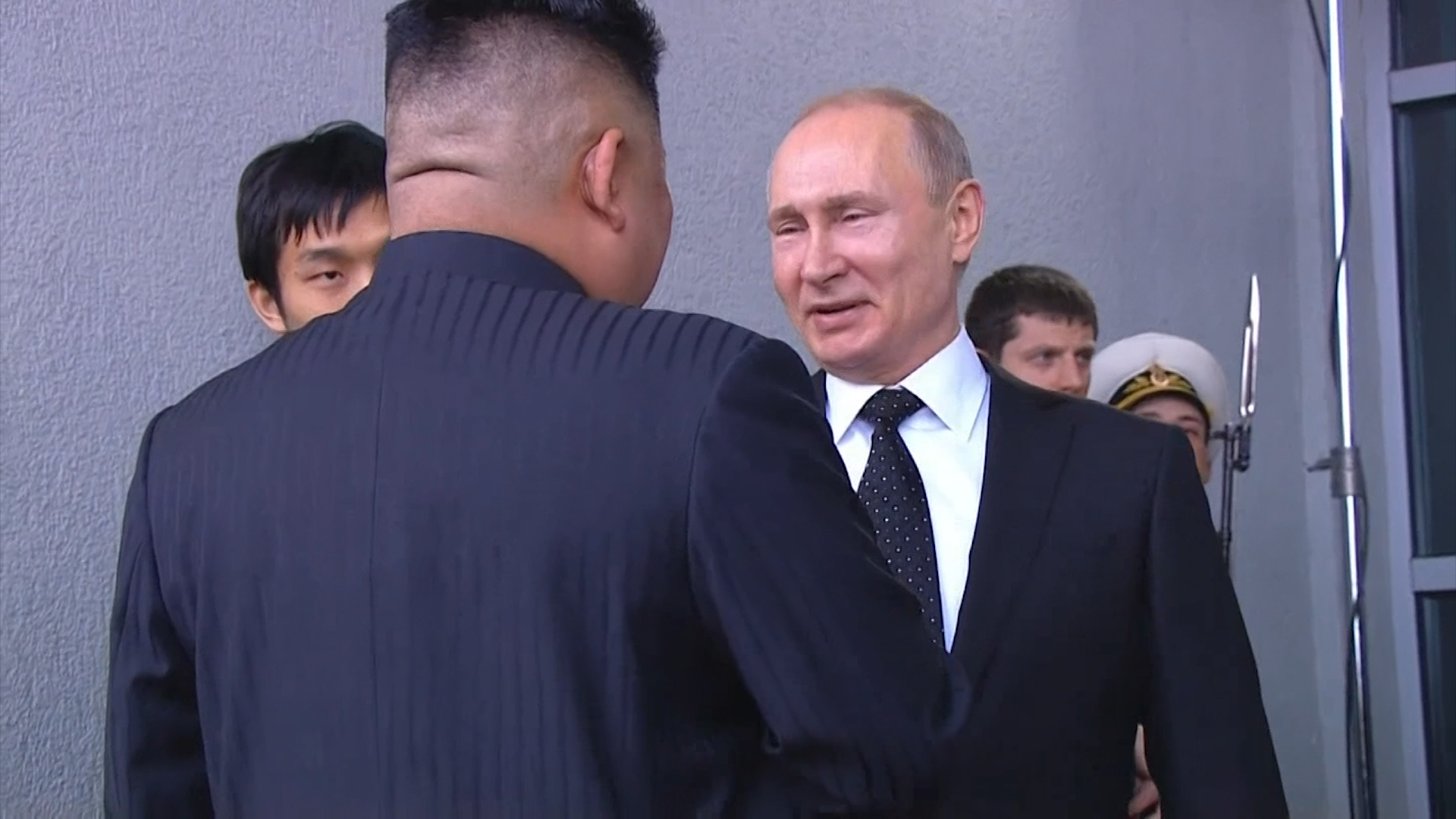 Putin and Kim shake hands outside a university building on Russky Island.