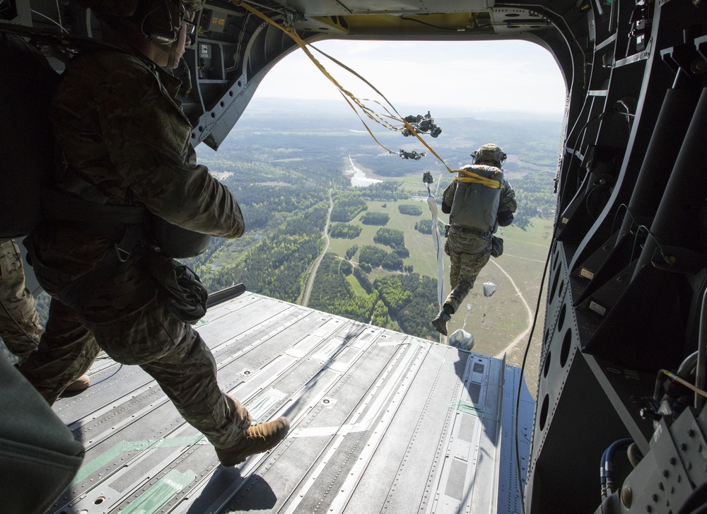 US army rangers parachuting from the back of a helicopter