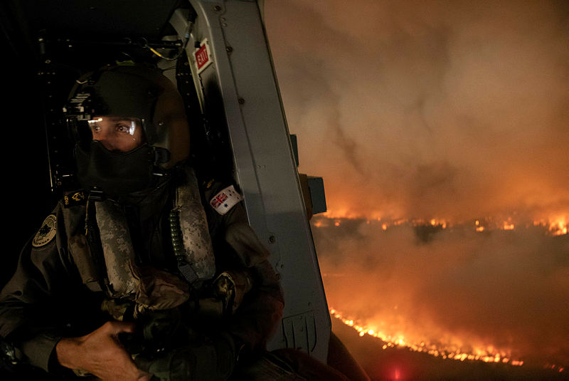 A Royal Australian Navy aircrewman over the wildfires in New South Wales (Picture: Australian Defence Force).