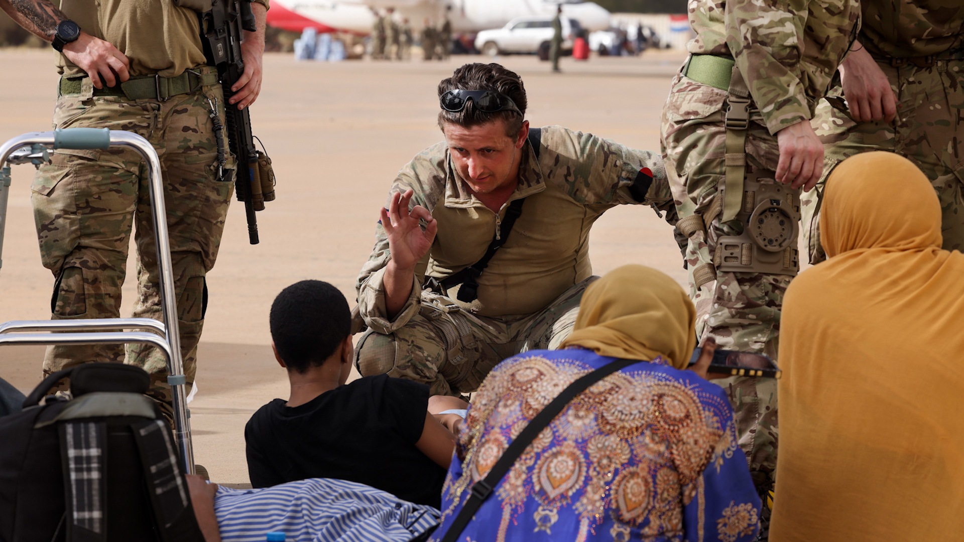 Royal Marine checks child waiting to board aircraft Cyprus Wadi Seidna airport Sudan 270423 CREDIT MOD