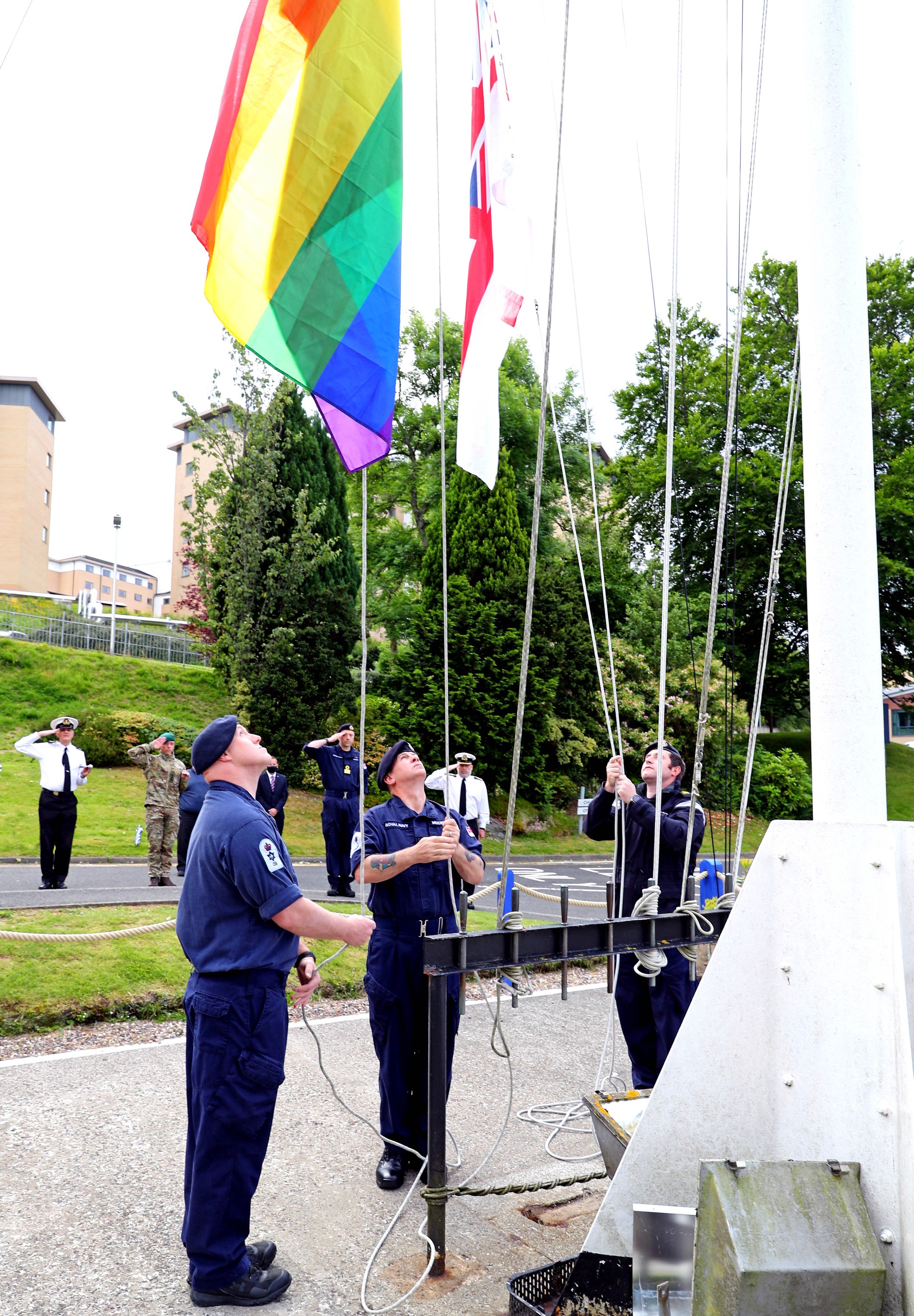 Royal Navy personnel, Babcock staff, MOD Civilian Staff, MOD Police watch as the Rainbow Flag is at raised at HM Naval Base Clyde during Pride Week