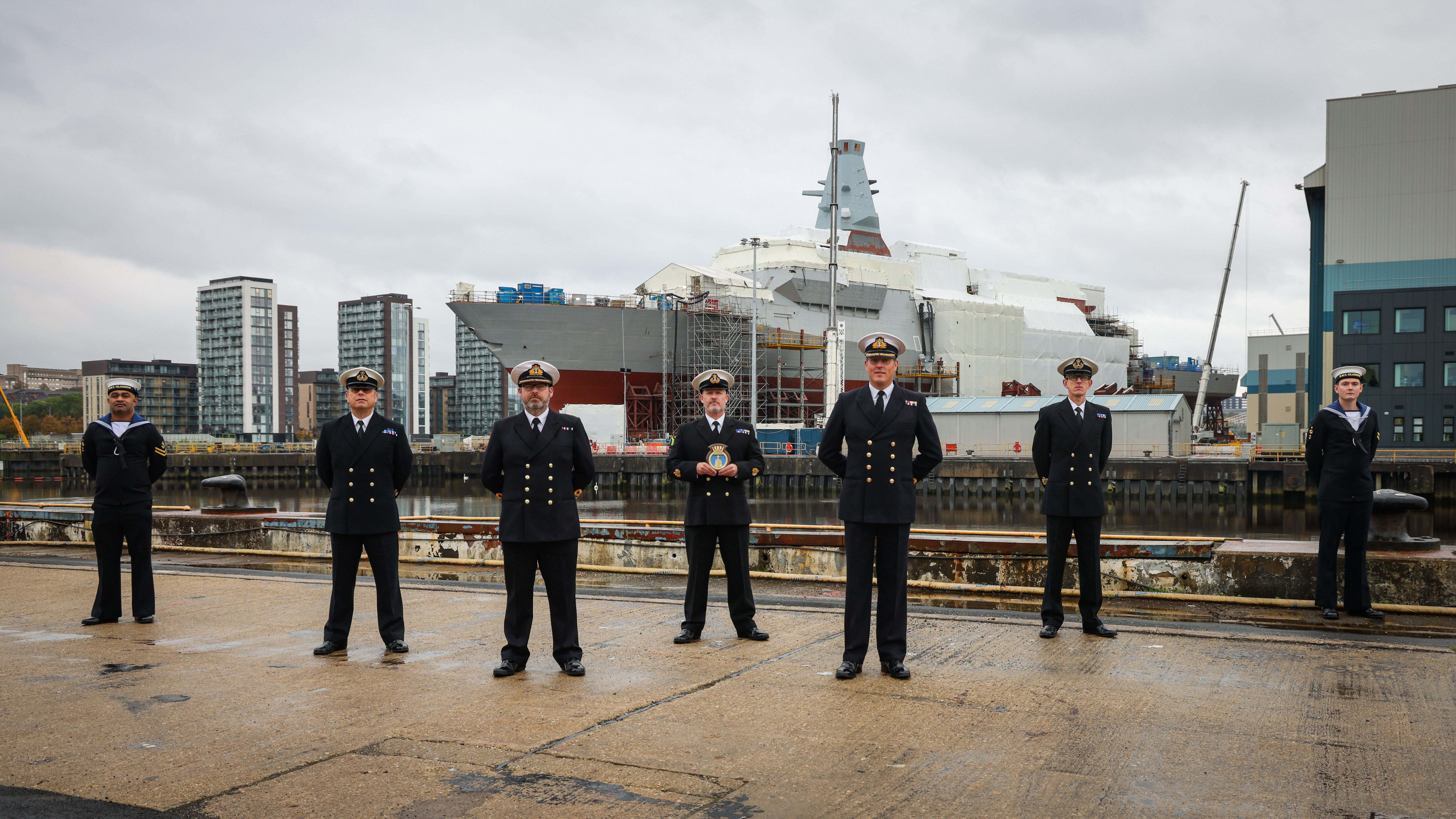 Sailors stand in front of the huge structure of HMS Glasgow under construction at Govan in Scotland (Picture: Royal Navy).