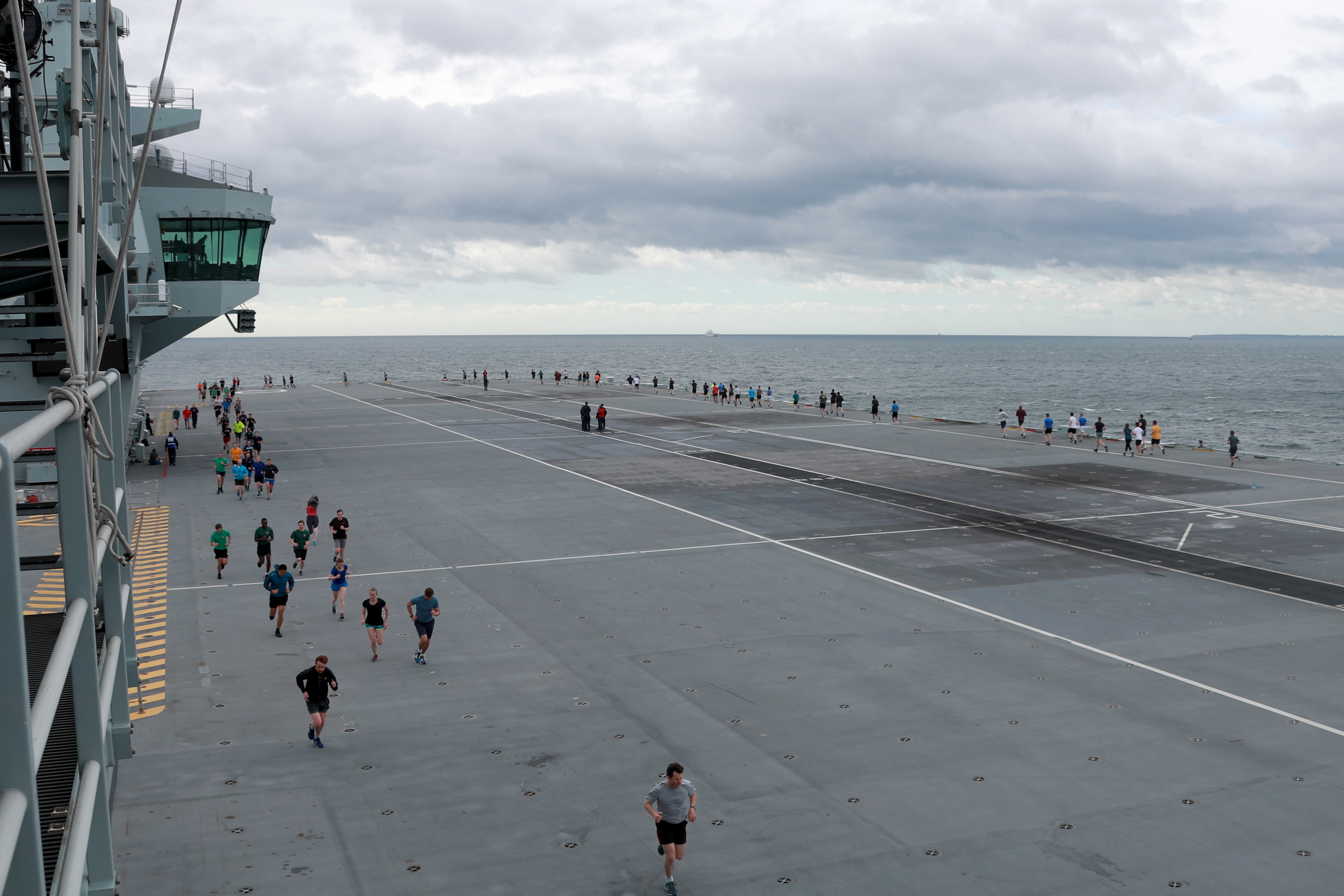 Personnel faced windy conditions as they ran 11 laps of the aircraft carrier's flight deck (Picture: Royal Navy).