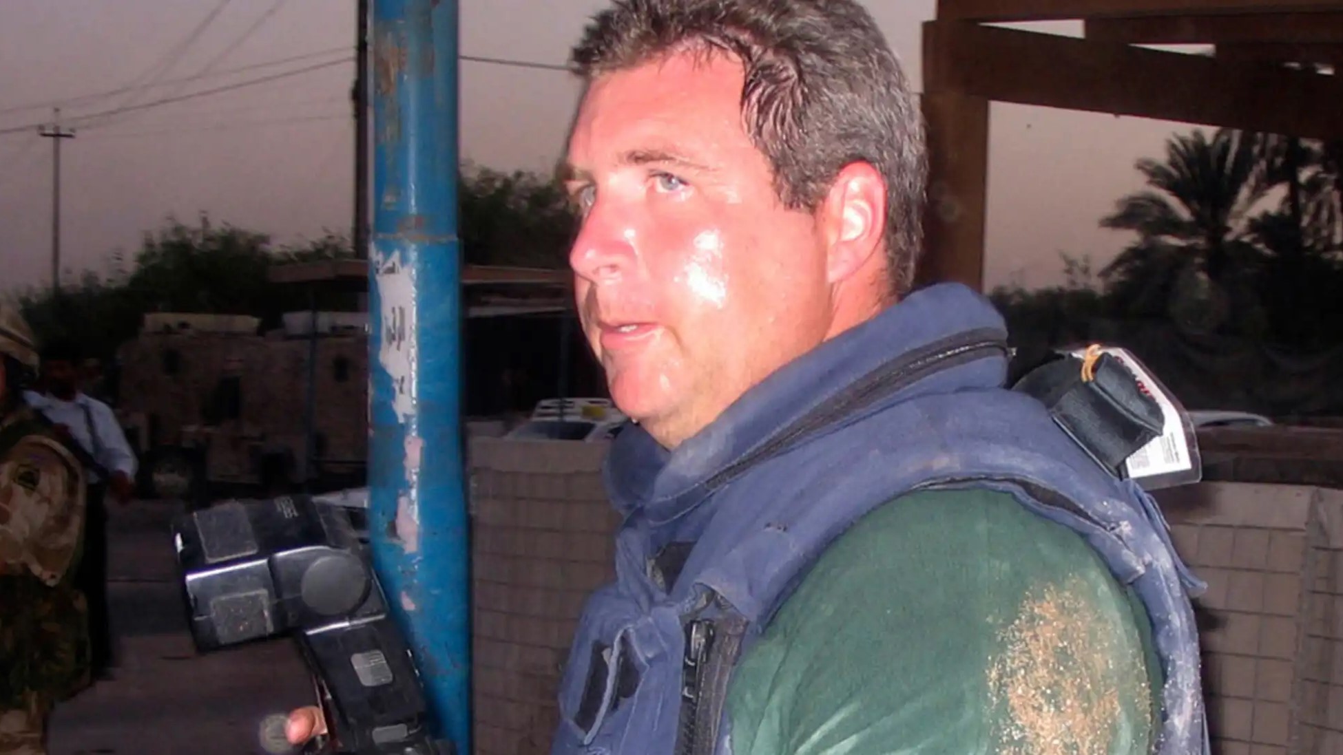 Soldier Magazine journalist seen with a camera wearing a bulletproof vest while in Iraq, a soldier can be seen in the background CREDIT Soldier Magazine