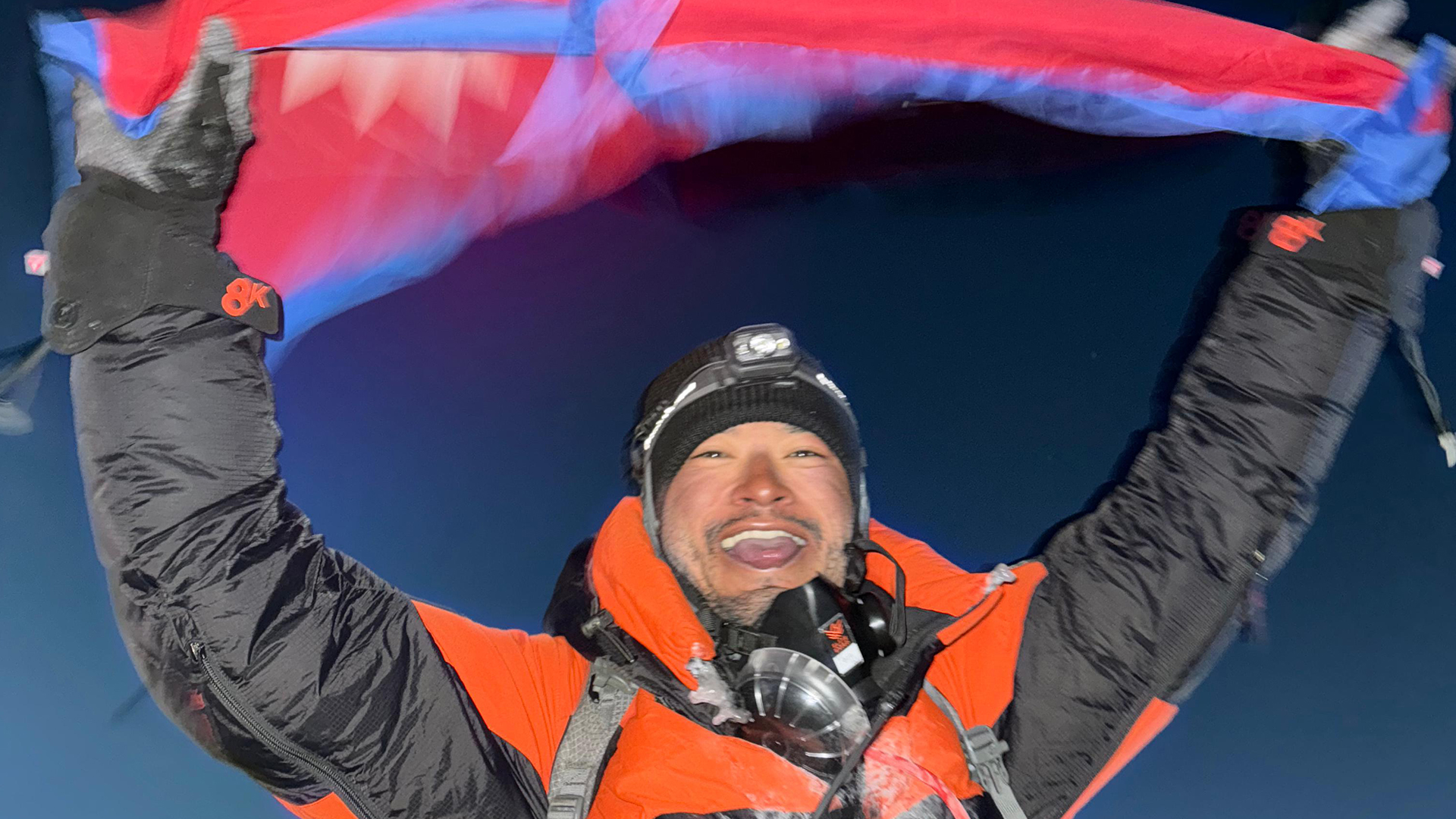 A triumphant Tejan Gurung waves the rectangular variant of the Nepalese national flag in homage to his roots (Picture: Elite Exped)