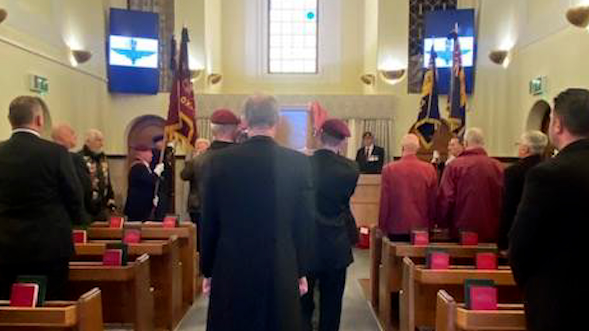 The coffin of LCpl Terence Purcell is carried into the chapel with the Parachute Regiment badge on the screens