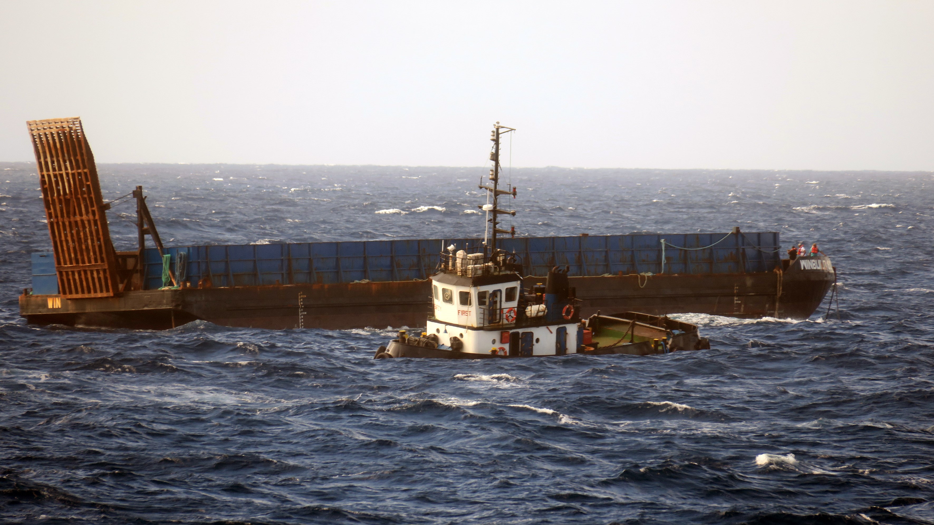 The stricken tug with the crew huddled on the bow of the sand barge it was towing 07012023 CREDIT Able Seaman Mitchell ‘Jack’ Macguire Royal Navy.jpg