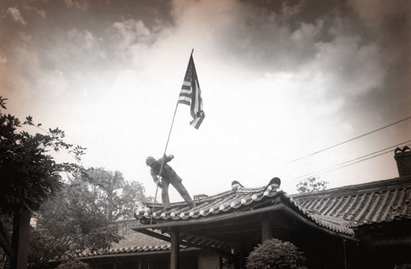 U.S. Marine raises the U.S. flag at the American consulate in Seoul, Korea, while fighting for the city raged around the compound, Sept. 27, 1