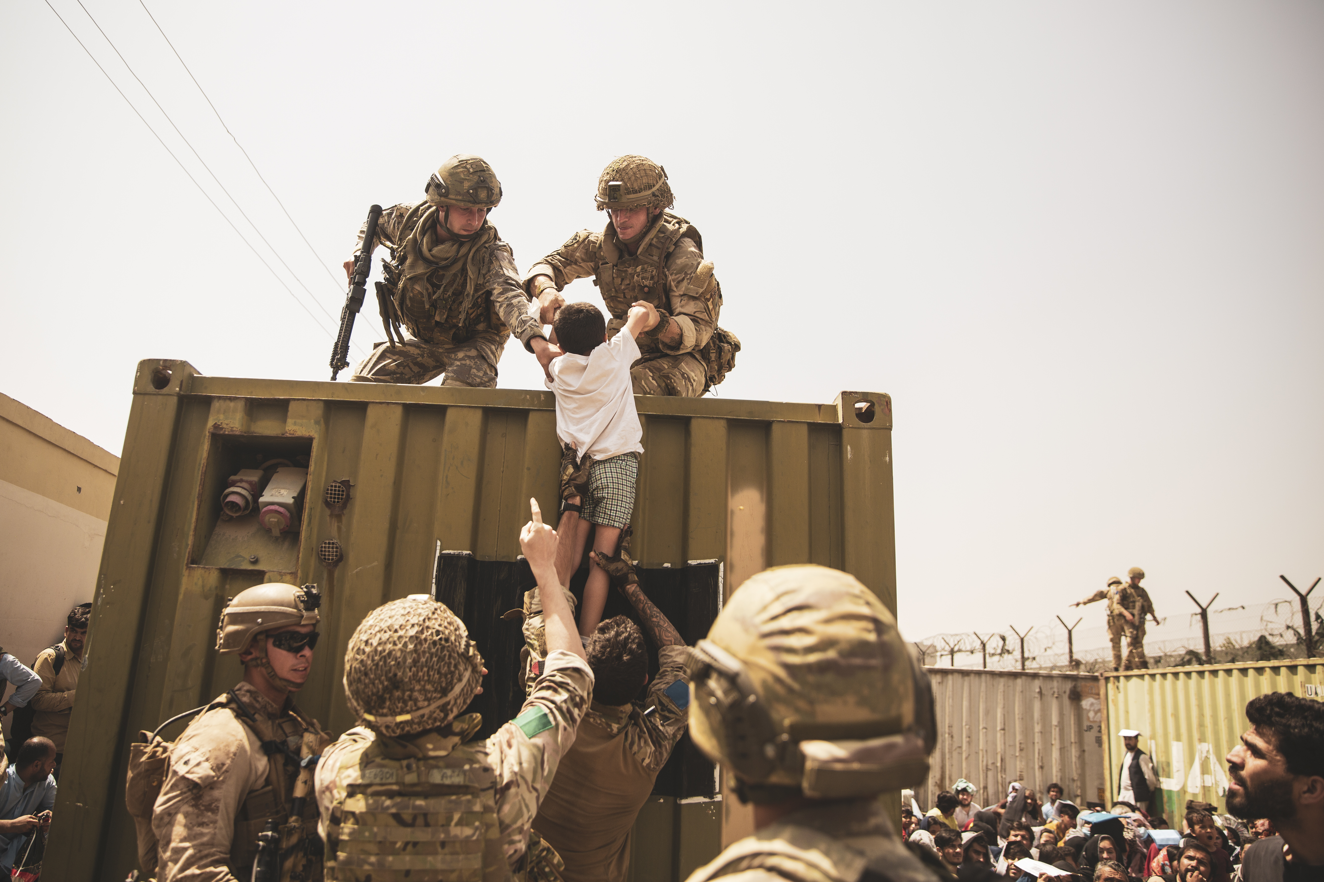 UK coalition forces, Turkish coalition forces, and US Marines assist a child during an evacuation at Kabul airport