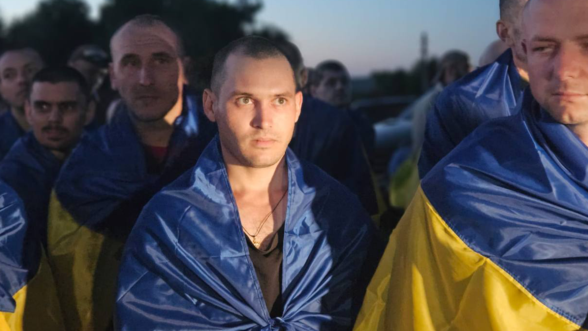 Ukrainian ex-prisoners of war are draped in their national flag as they return home after being released (Picture: President Zelensky's Telegram channel)