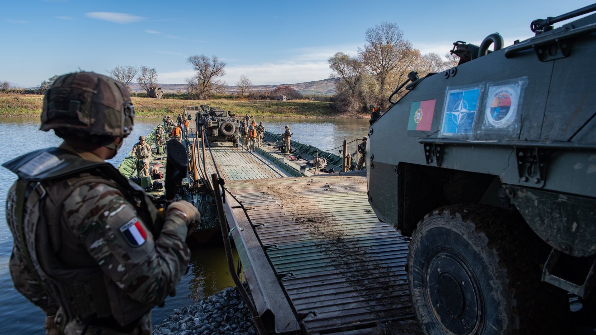 French armoured vehicles and Romanian trucks boarded a motorised floating bridge during the exercise
