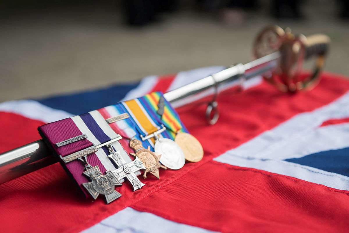 Victoria Cross shown with other medalsshown next to a ceremonial sword on a Union Jack