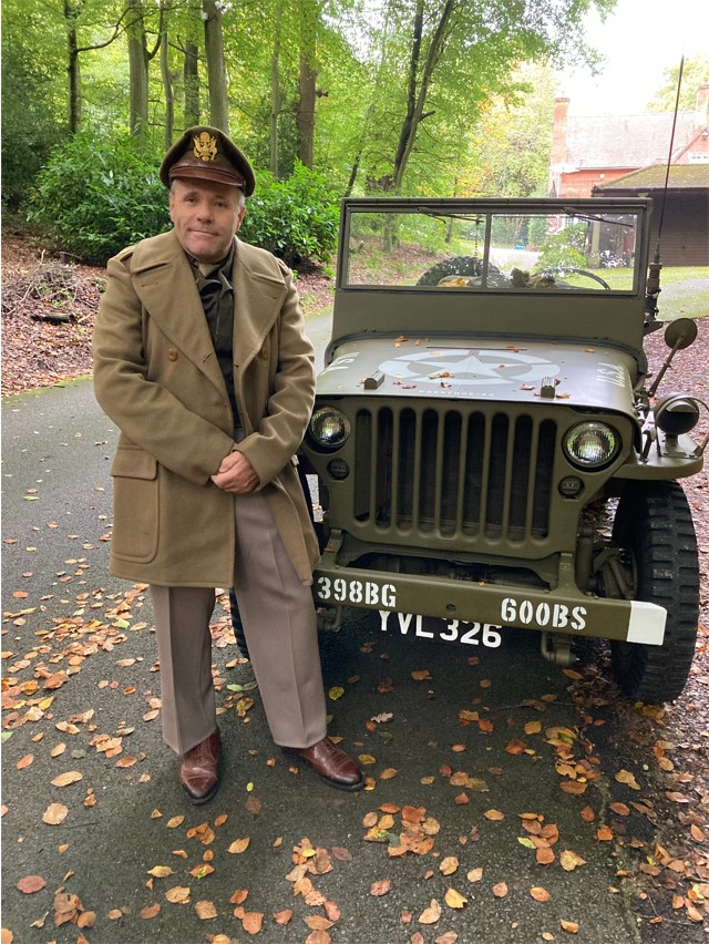 WW2 re-enactor standing in front of his restored jeep