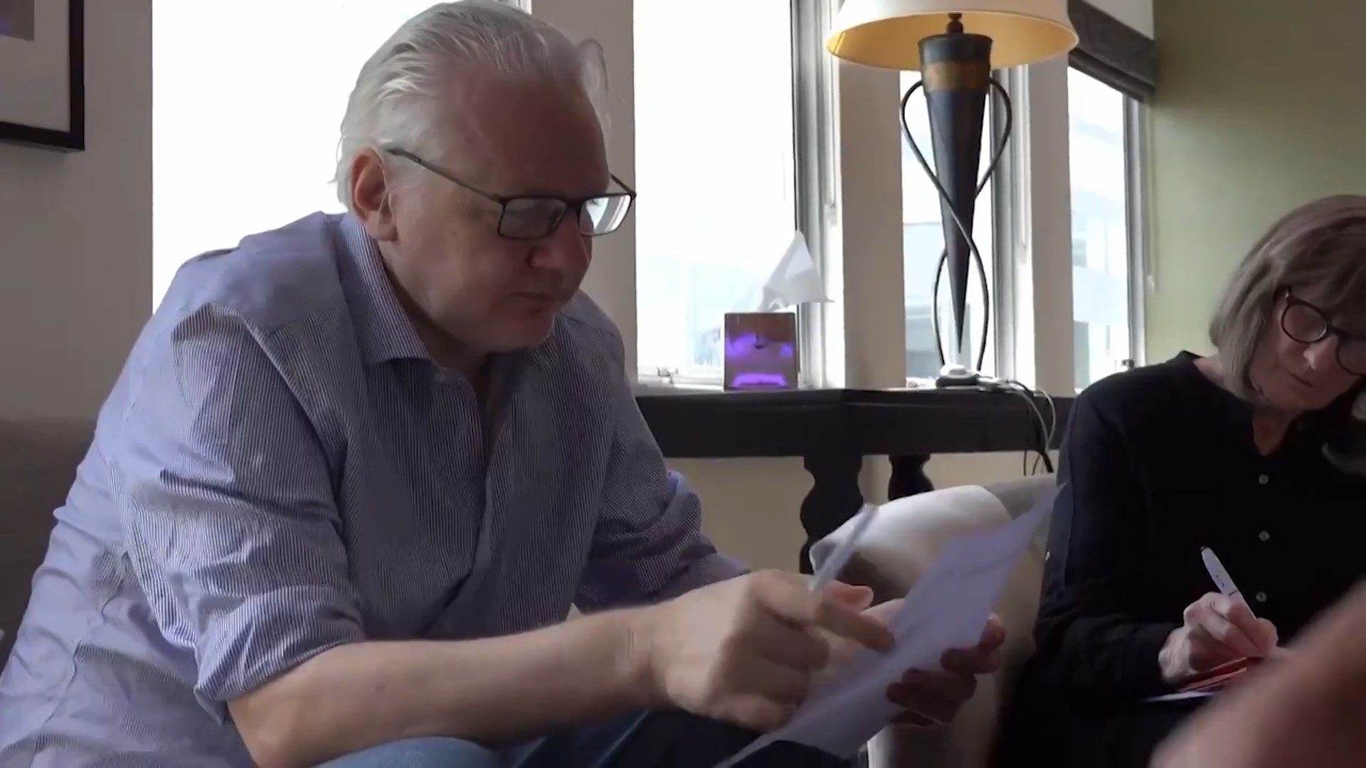 Julian Assange discusses the text if his plea deal on a sheet of paper following his release from Belmarsh (Picture: Reuters).