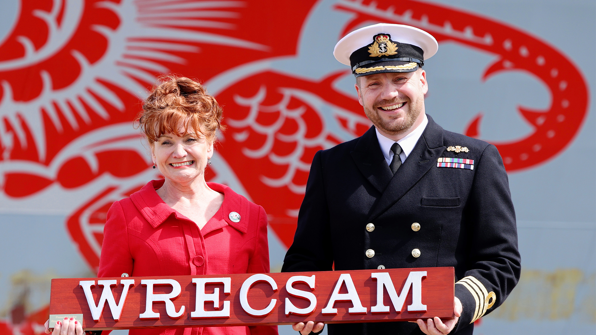 Wrexham MP Sarah Atherton and HMS Dragon's Commanding Officer, Commader Iain Giffin, with the name of the city using the Welsh spelling (Picture: MOD)