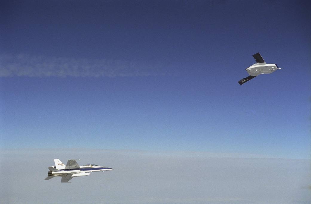 X-45A in flight with F-18 chase aircraft, during first GPS-guided weapon demonstration flight