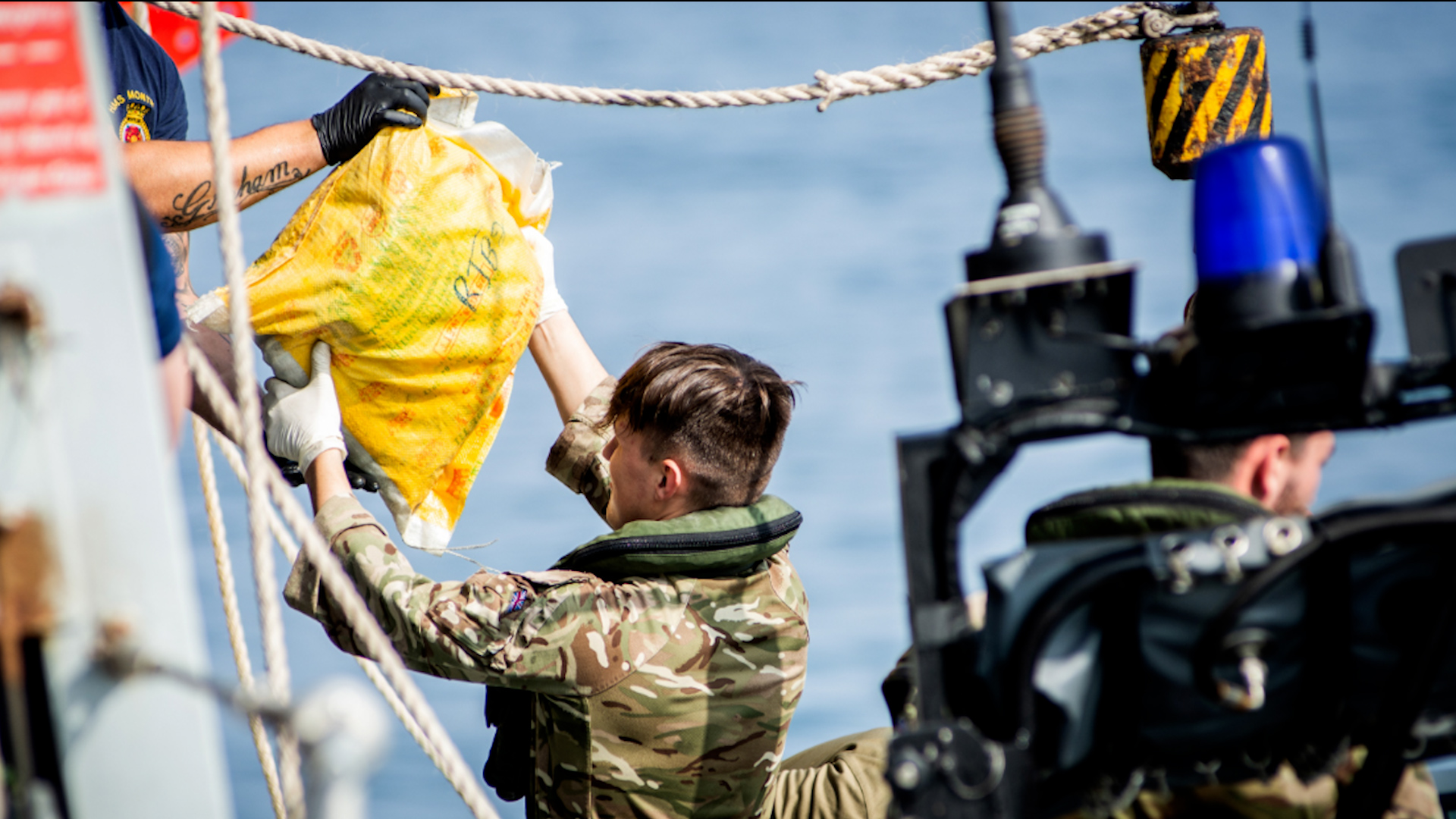 A Royal Marine hands a sailor on HMS Montrose a sack of hashish to be destroyed (Picture: Royal Navy).
