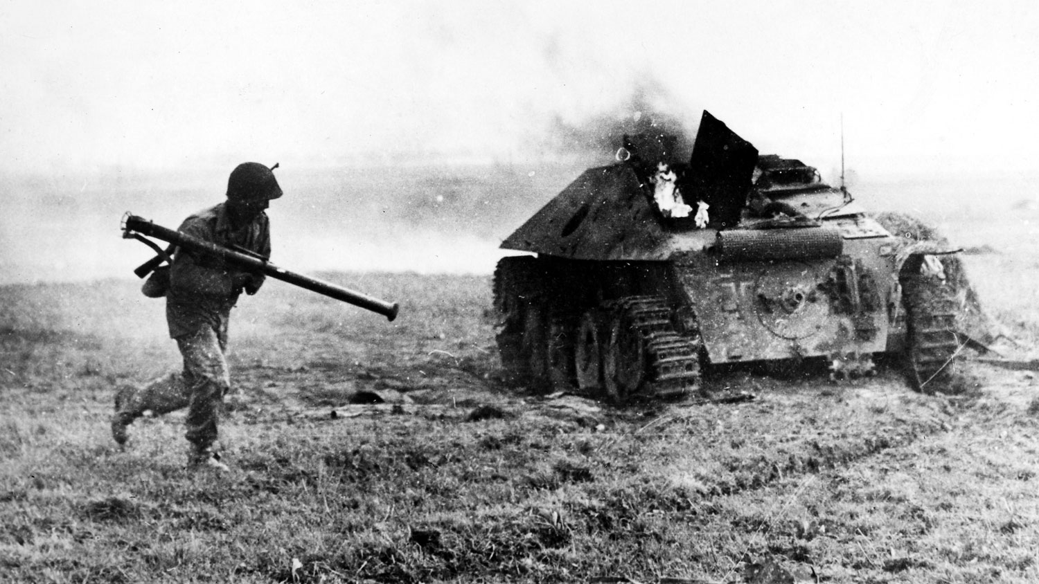 Image ID FFD04N a 9th Army soldier with a bazooka runs past a burning German tank destroyer near Aldenhoven, Germany in December 1944 CREDIT GRANGER - Historical Picture Archive / Alamy Stock Photo