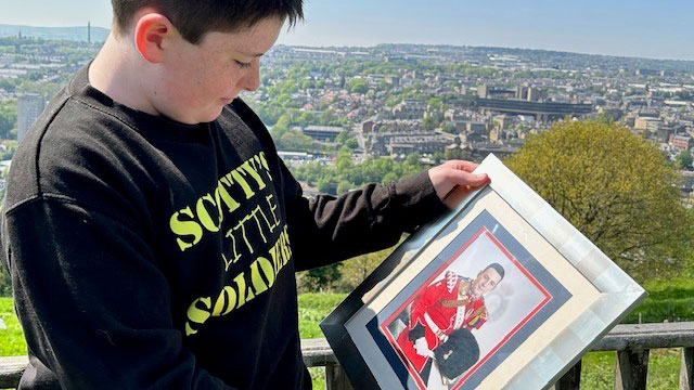 Jack Rigby holding a photo of his dad Lee Rigby CREDIT Scotty's Little Soldiers