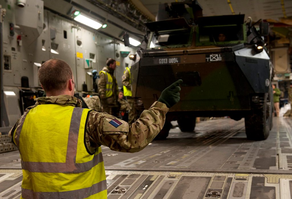 A Royal Air Force serviceman directs the loading of a French armoured vehicle onto a C-17 at Evreux, France, as the UK assists France to move military equipment to Mali, West Africa.