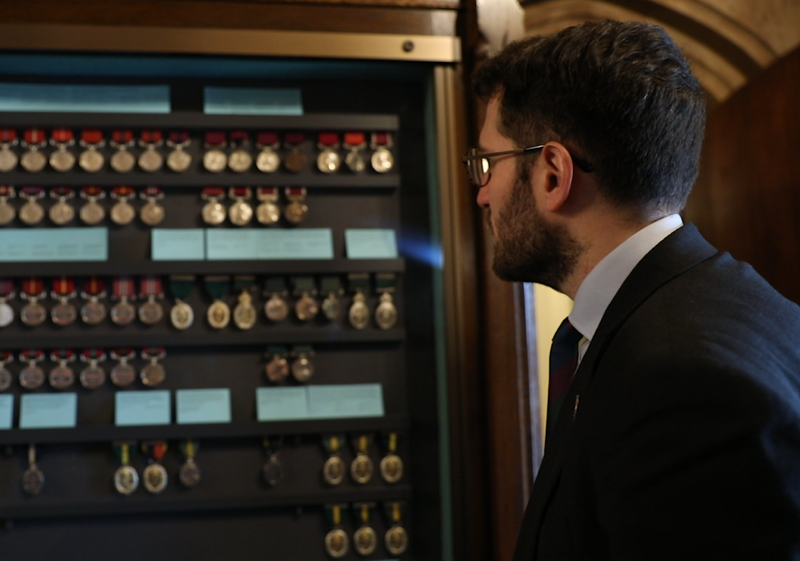 Paul Sweeney MP gazes at military medals in the Houses of Parliament