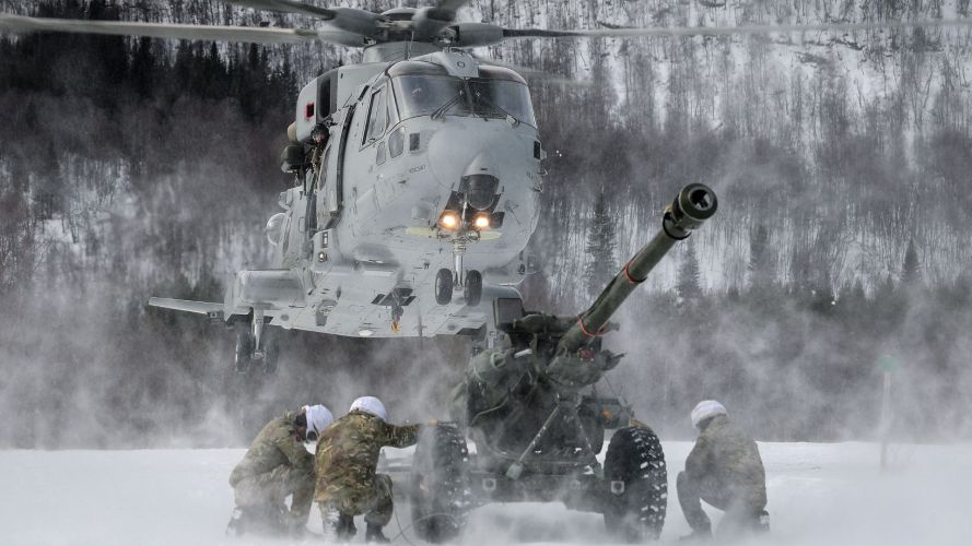 Personnel from 29 Commando Regiment Royal Artillery deployed in Norway shelter from downwash as they wait with a 105mm Light Gun to be lifted